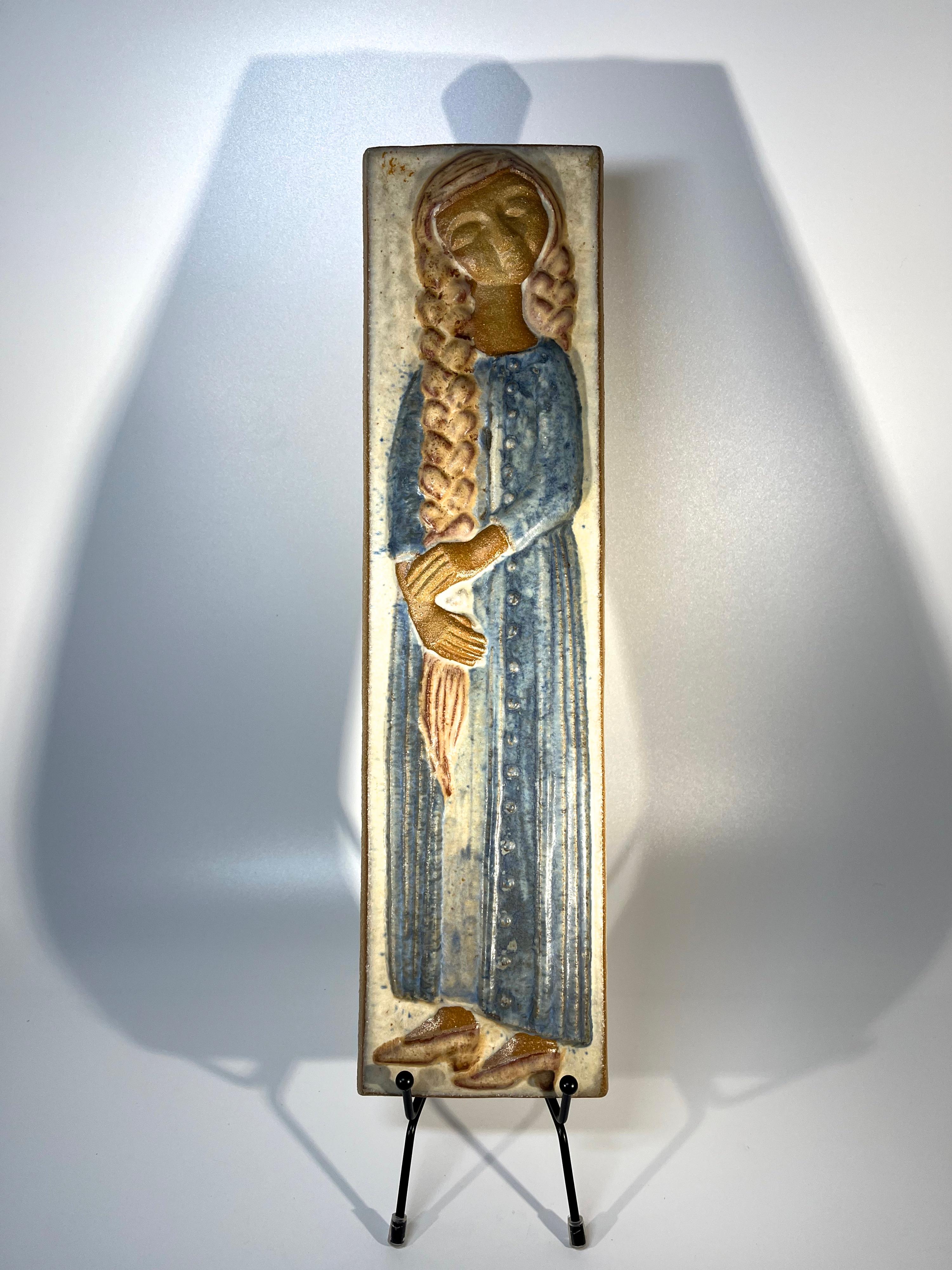 Mädchen mit geflochtenem Haar Wandtafel, von Marianne Starck für Michael Andersen, Dänemark 
Gelassenes Bild, ergänzt durch  zart blassblaue Glasur
Gestempelt MS, Dreiheringe-Marke und #6056 auf der Rückseite
Breite 4 Zoll, Höhe 15 Zoll, Tiefe 1