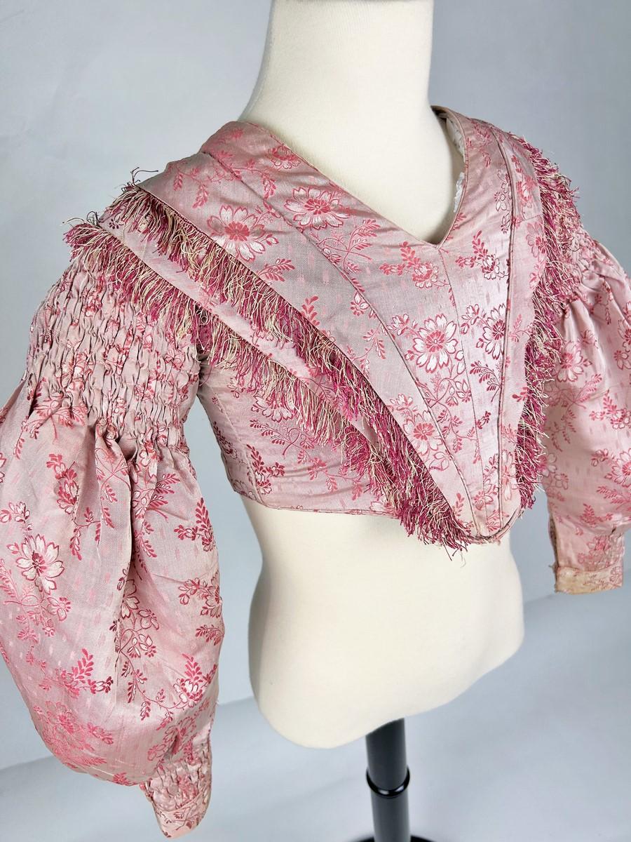 Circa 1850
Francia o Europa
Corpetto da giorno da ragazza in taffetà di seta rosa risalente alla fine del periodo francese Louis Philippe. La seta ha un fondo in twill ed è broccata con bouquet di fiori bianchi e rosa. Il corpetto è curvo con una