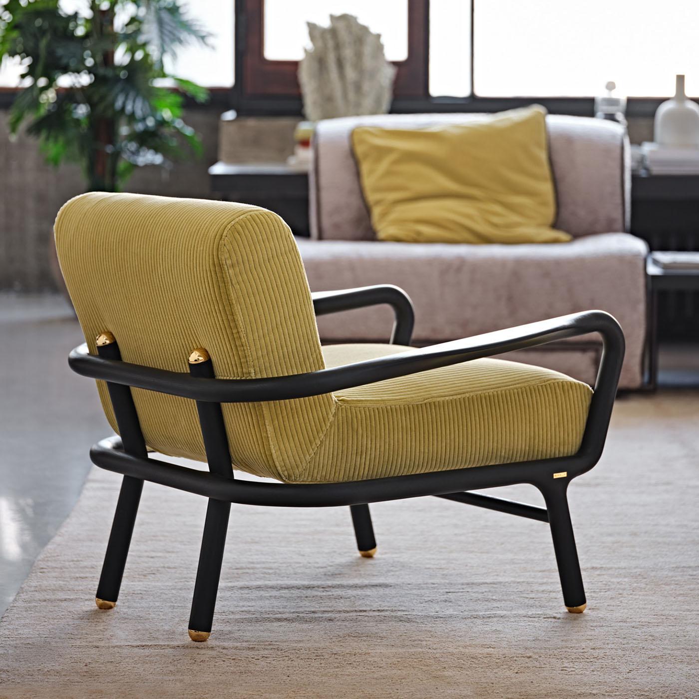 Clean and dynamic lines outline the modern silhouette of this armchair, whose seat's indulging silhouette makes it perfect for resting in the company of a good book. Glossy golden details accent the tips of its cylindrical solid ash frame, stained