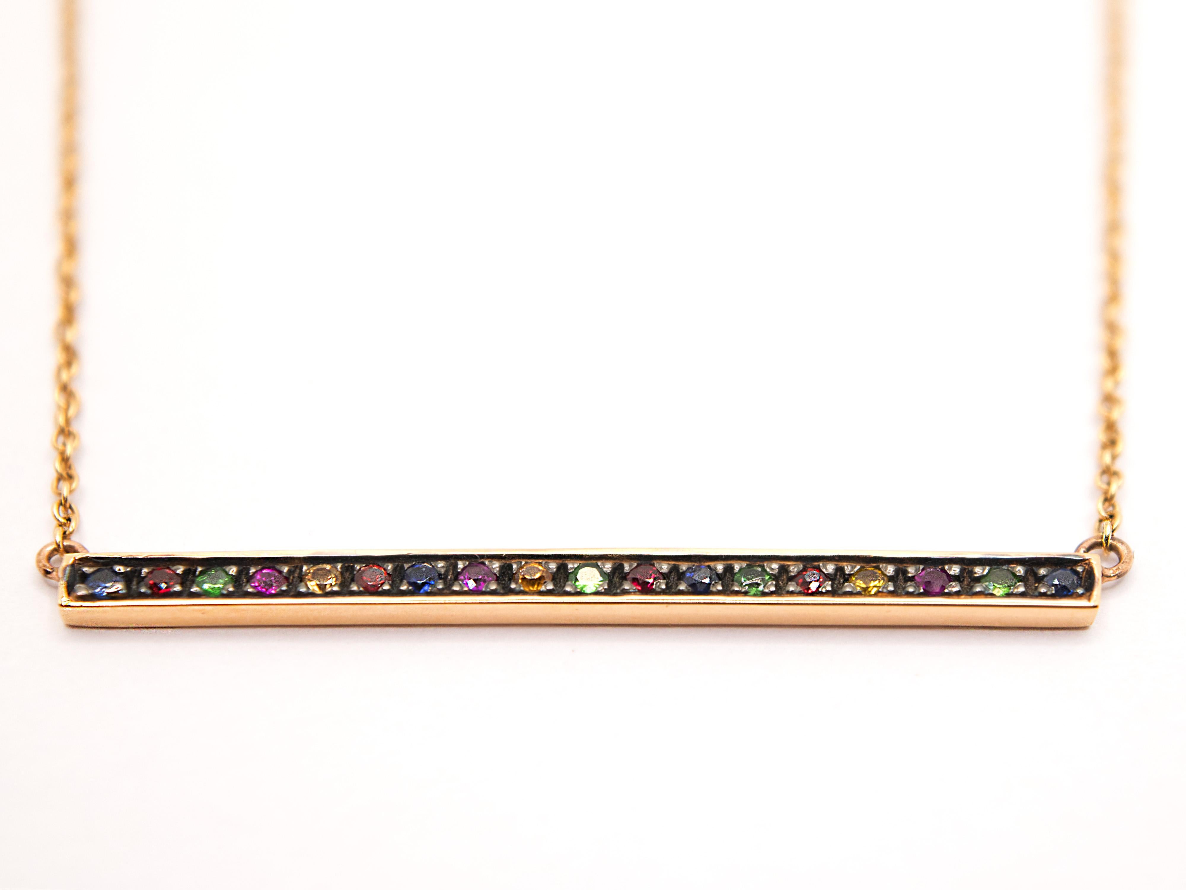 Ce collier en or rose 18kt est fabriqué à la main en Italie.

La barre centrale est composée de saphir, de grenat et de rubis, tandis que les pointes qui retiennent les pierres ont été brunies pour les faire ressortir davantage.

La chaîne rolo qui