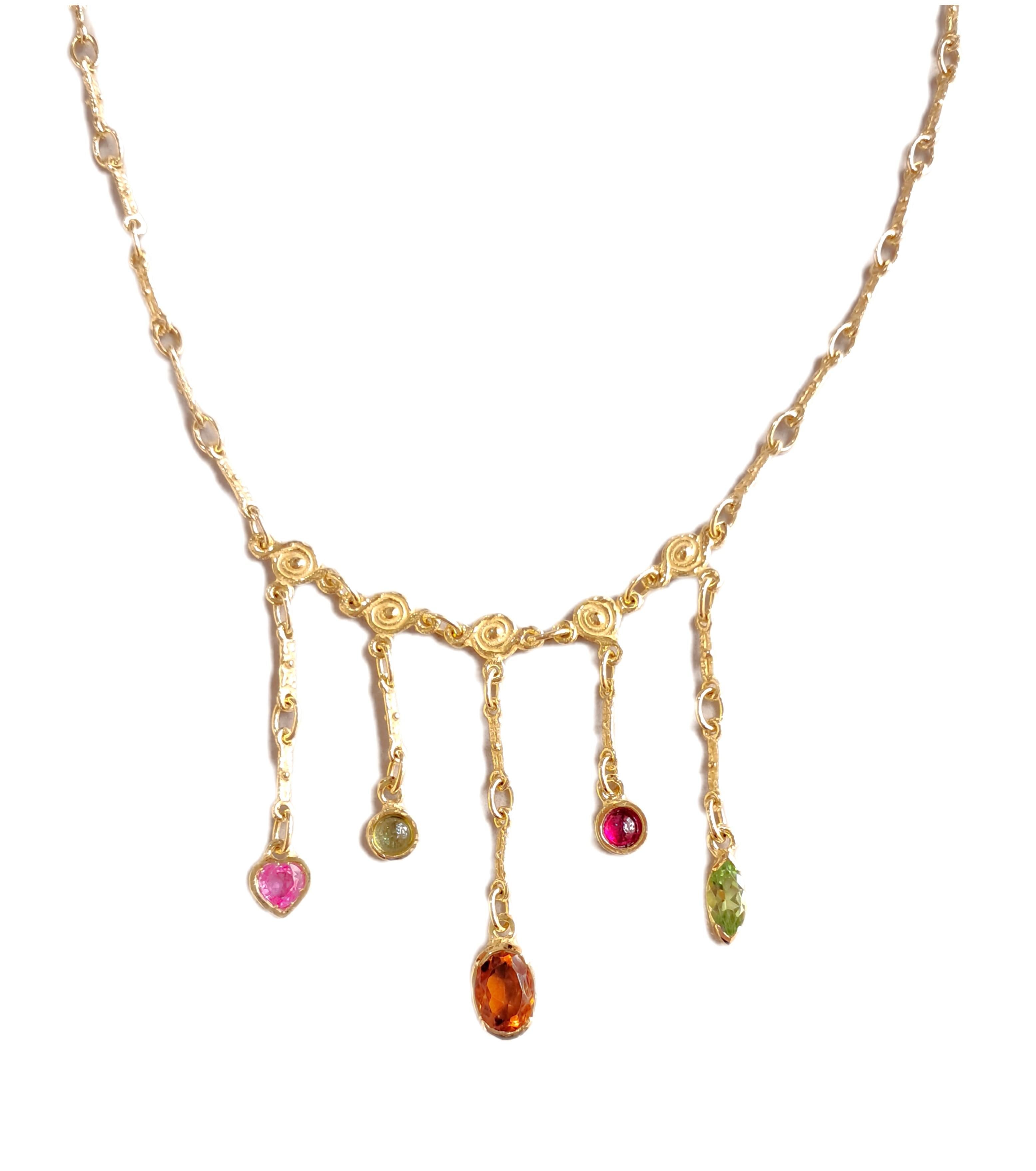 Collana è realizzata in oro giallo satinato 18 carati impreziosito da centrali con pietre di diversi colori e tagli.  Zaffiro Rosa taglio a Cuore, Peridoto taglio Cabochon, Topazio giallo taglio Ovale, Tormalina taglio Cabochon, Peridoto taglio