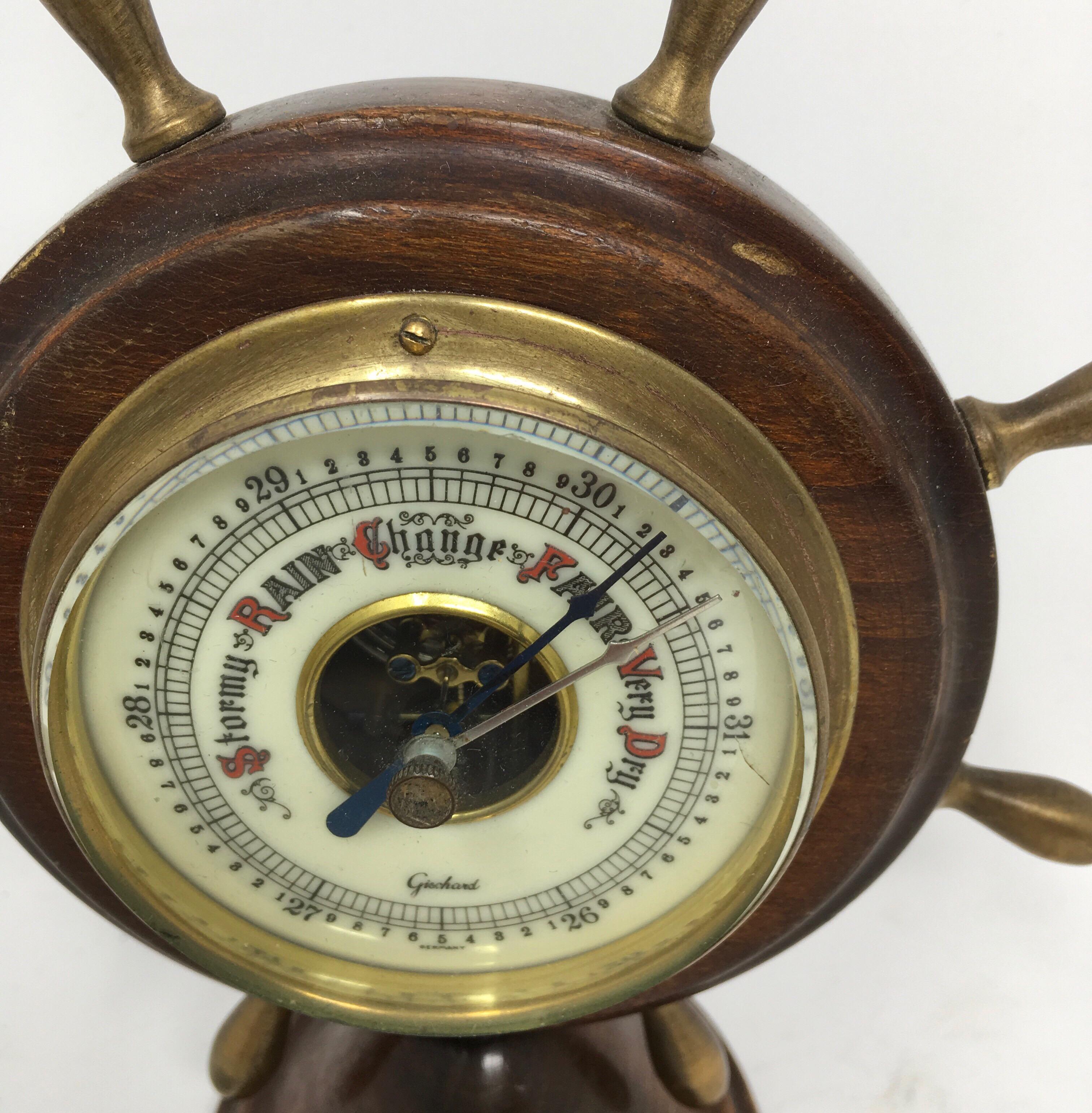 Vintage ships wheel aneroid barometer by Gischard of Germany, circa 1950s. The ceramic face is beautifully detailed with a brass bezel and printed signature. The barometer is complete with brass finials and sits on a pedestal base.