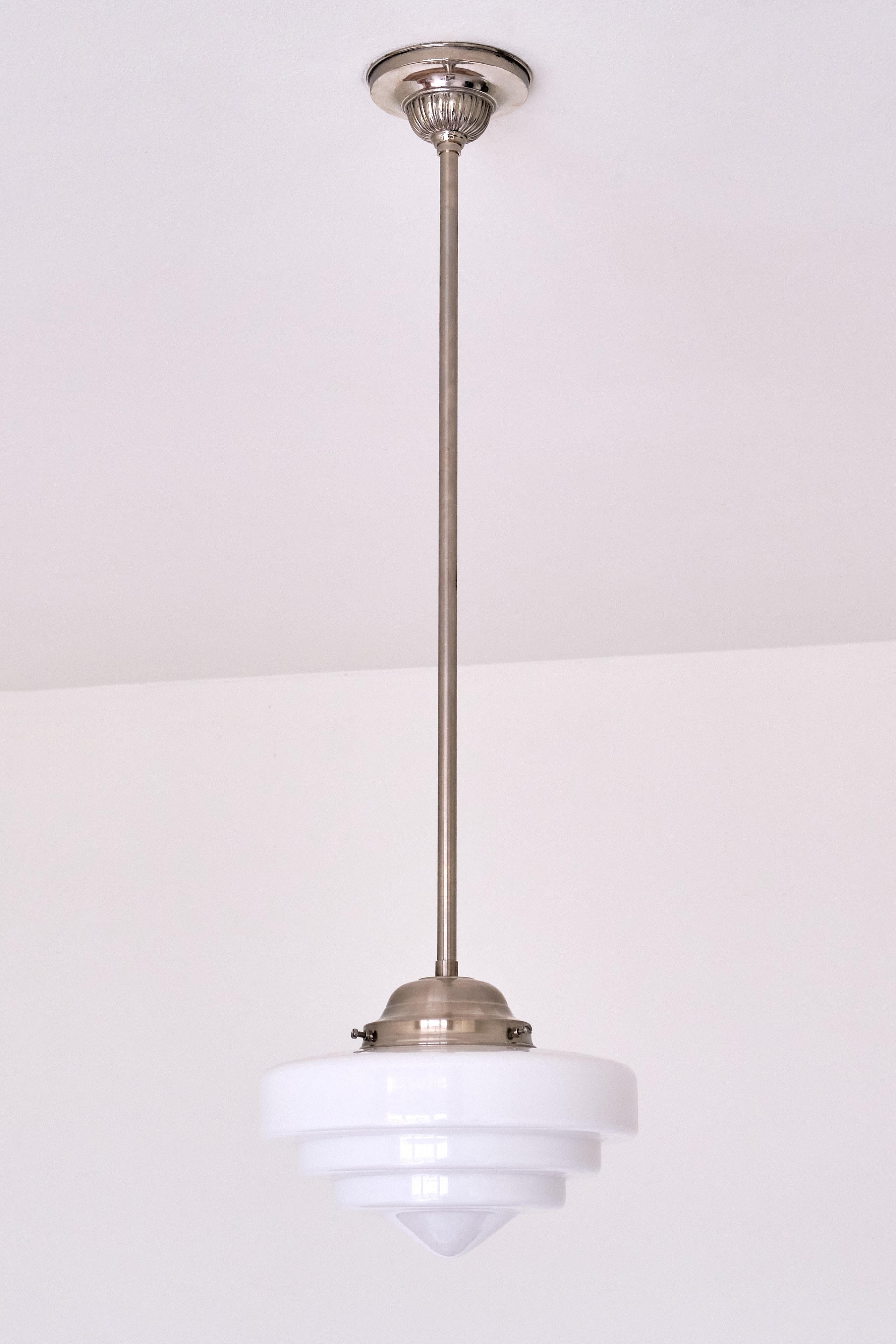 This rare pendant light was produced by Gispen in The Netherlands in the 1950s. The striking shade is in a three tiered, cascading shape ending in a rounded flattened cone shape. The shade is made of a slightly glossy, white opaline glass. The shade