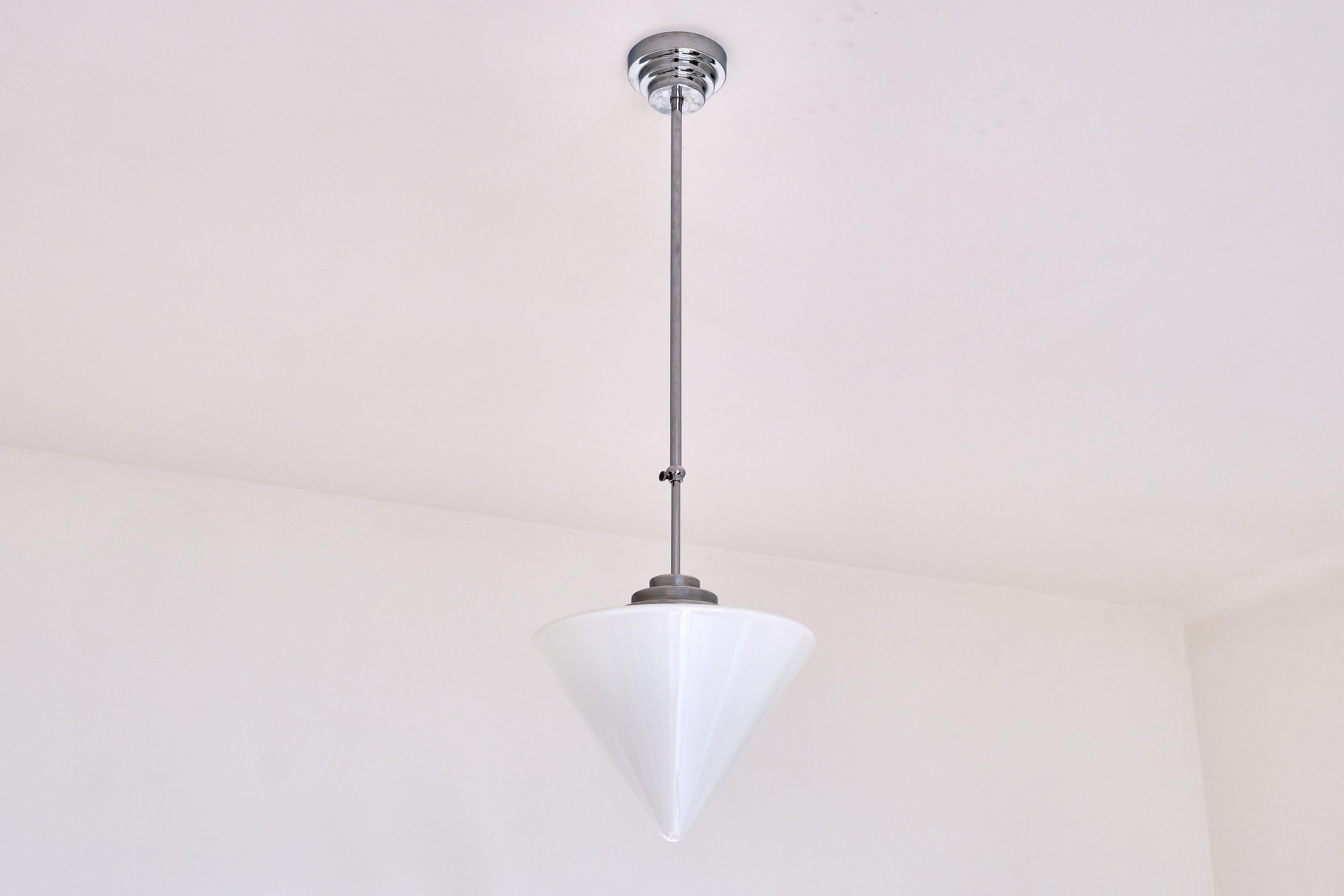 This rare pendant light was produced by Gispen in The Netherlands in the 1950s. The striking cone shaped shade is made of a slightly glossy, white opaline glass. The shade is attached to the pendant fixture made in a glossy nickel, with a beautiful