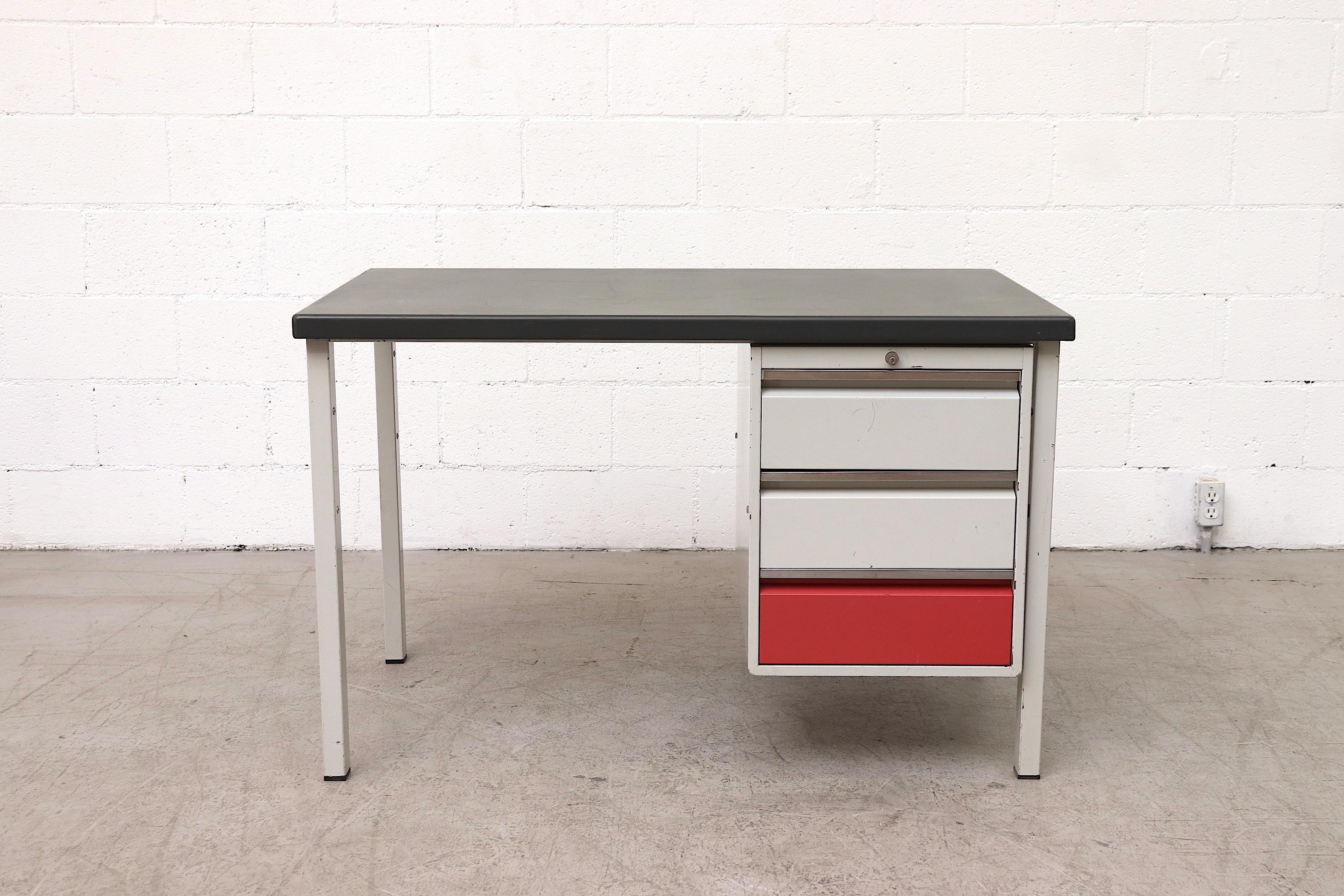 Midcentury industrial metal desk with light grey enameled metal frame. Side stacked red and white enameled metal drawers with grey linoleum top. Original condition with visible wear, some scratching and metal loss. Wear is consistent with age and