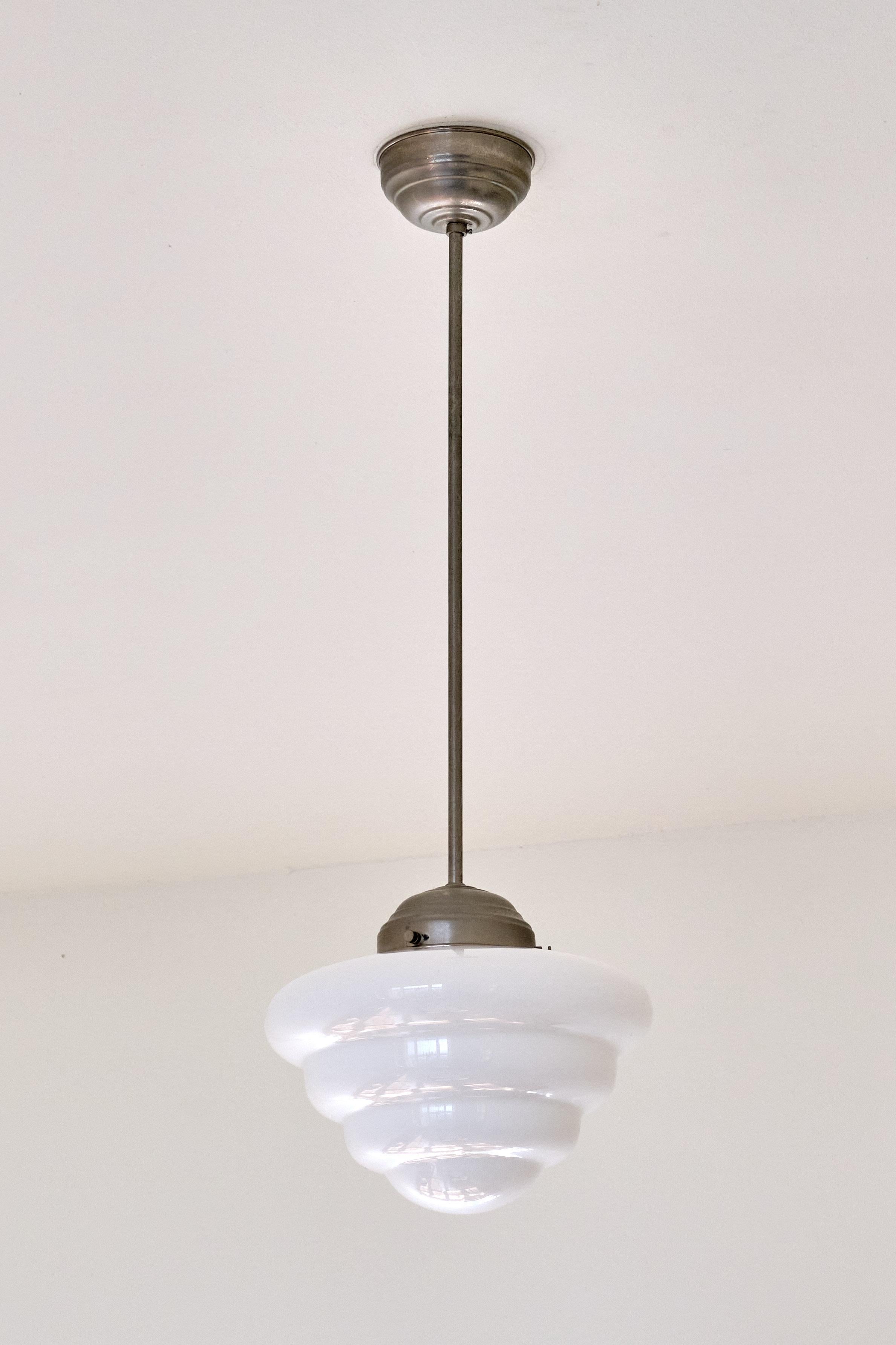 This rare pendant light was produced by Gispen in The Netherlands in the 1930s. The striking shade is in a four tiered, cascading and entirely rounded shape. The shade is made of a slightly glossy, white opaline glass. The model of the shade was