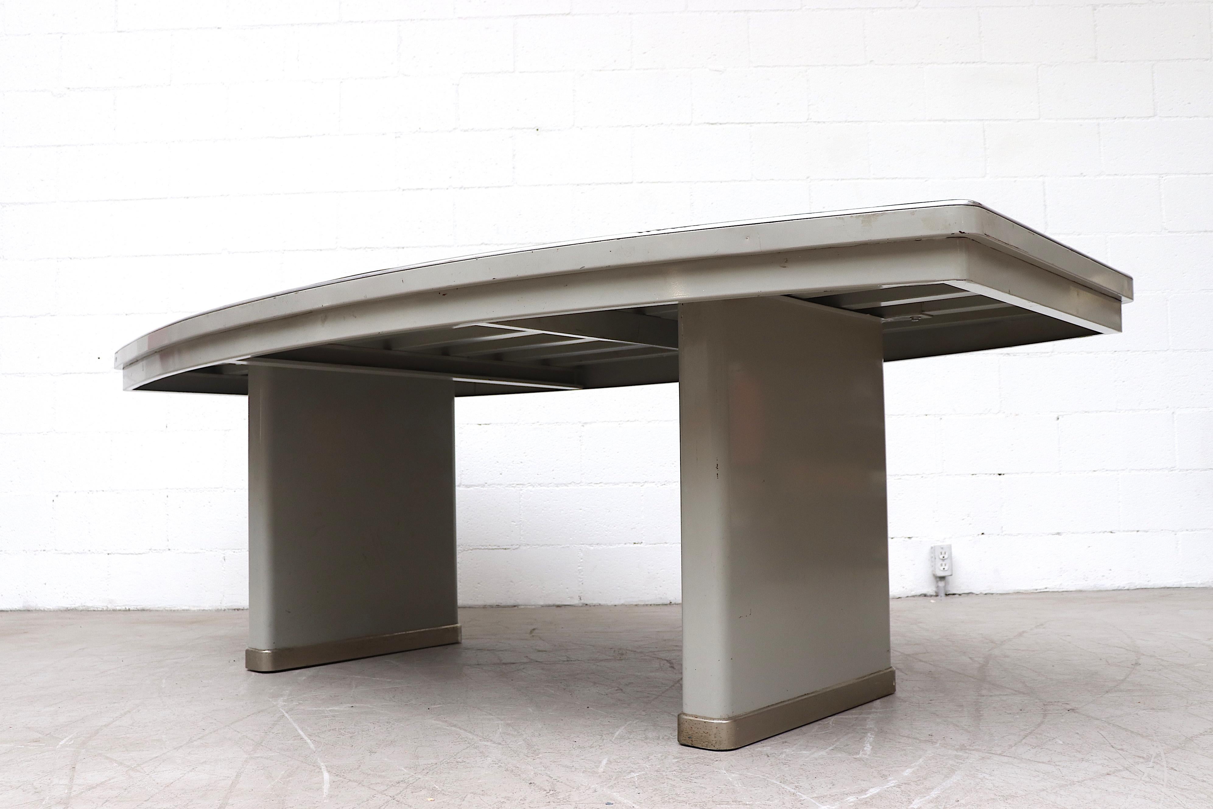 Impressive industrial conference table by Lips with grey enameled metal frame, bowed dark grey linoleum top with metal trim and large metal legs. In original condition with visible wear and scratching, including some denting to the metal edge.