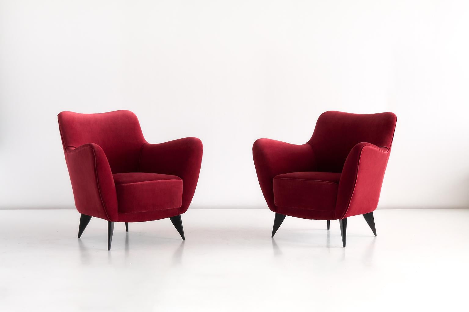 This pair of Perla armchairs was designed by Giulia Veronesi and produced by ISA Bergamo, Italy. Its sensual curves and the elegantly tapered legs give the chair a sculptural and modern feel. The armchairs have been fully reconditioned and newly