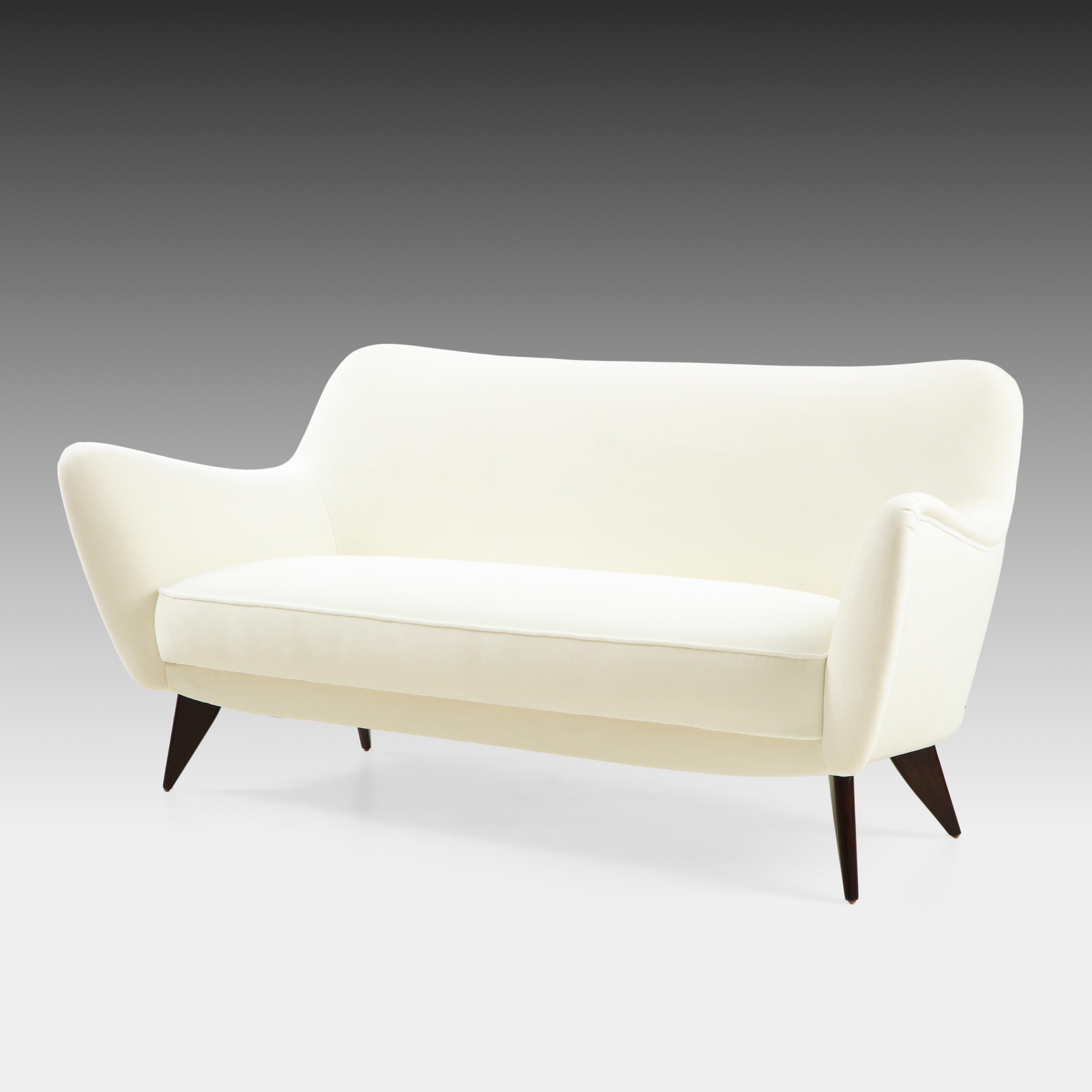 Giulia Veronisi for ISA Bergamo elegant and sculptural ivory velvet Perla sofa with slightly curved back and gently outstretched arms ending in signature sharply tapered flat triangular walnut legs, Italy, 1950s. This chic model features beautiful