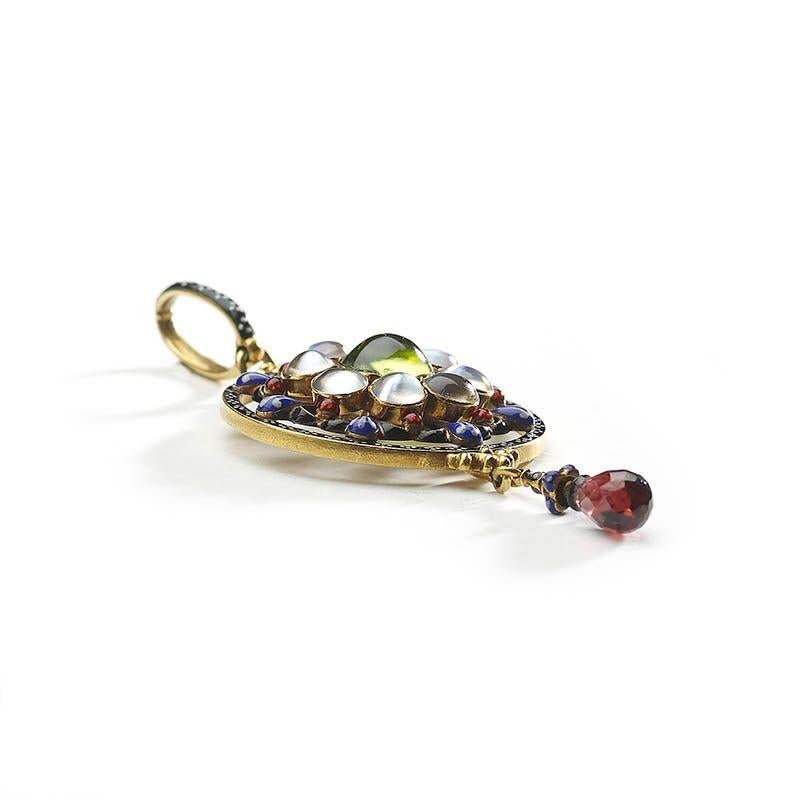 A Carlo Giuliano enamel, peridot, moonstone, garnet and gold pendant with a cabochon-cut peridot, in the centre of a cluster of eight, cabochon-cut moonstones, with a blue, white, black and red enamelled fleur-de-lys surround, bordered by a circle