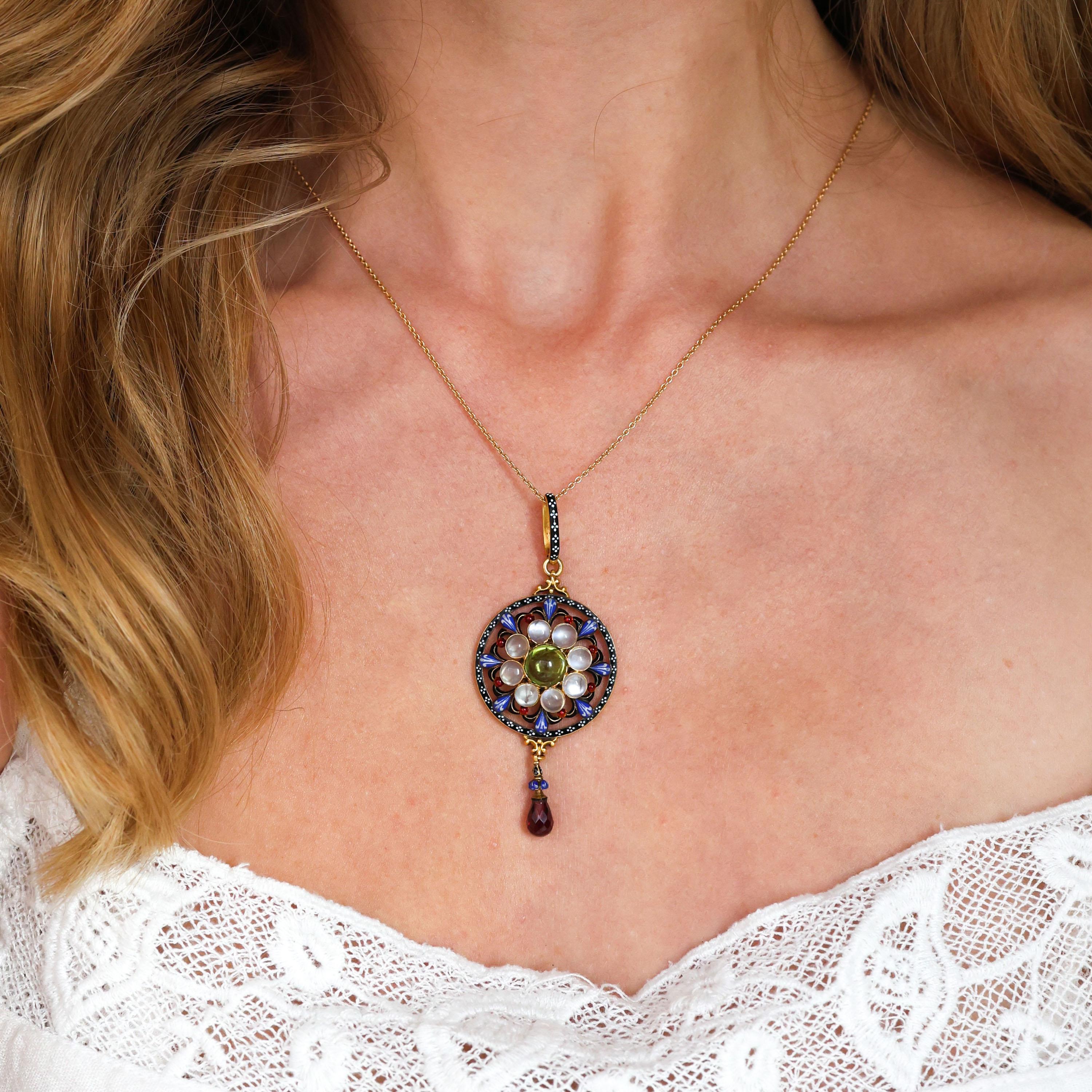 Pendentif en émail, péridot, pierre de lune, grenat et or de Carlo Giuliano avec un péridot taillé en cabochon au centre d'une grappe de huit pierres de lune taillées en cabochon, entouré d'une fleur de lys émaillée bleu, blanc, noir et rouge,