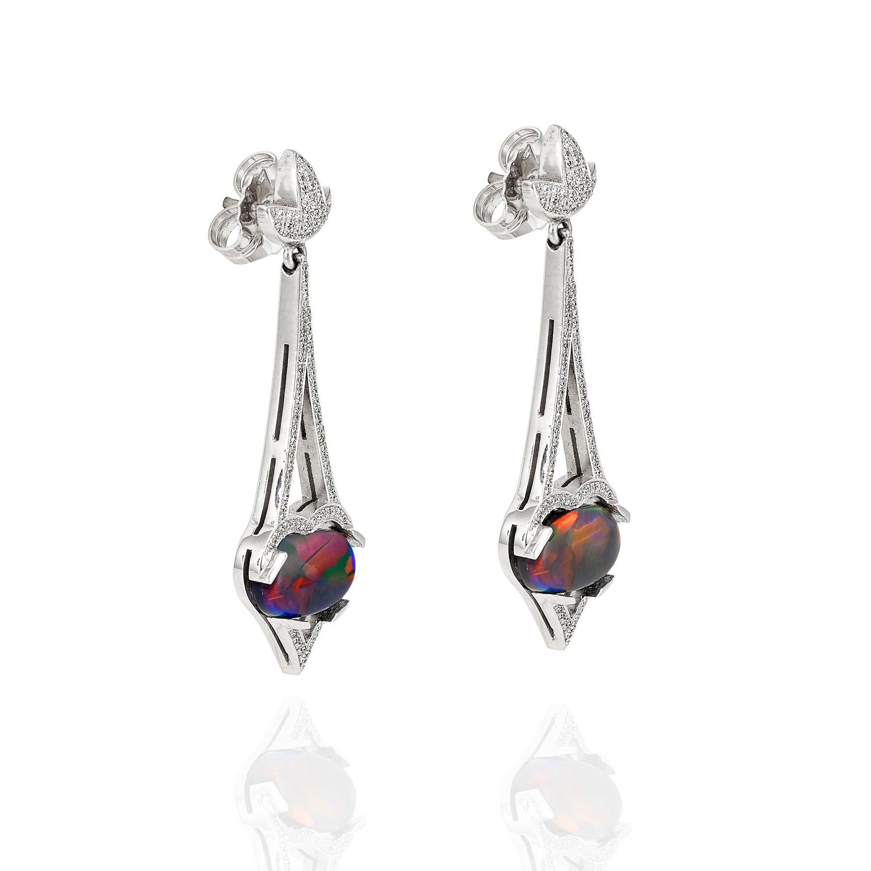 Giulians 18 karat white gold Art Deco inspired black opal and diamond drop earrings.  These earrings feature two oval cabochon, natural, solid Australian opals from Lightning Ridge, NSW (total weight 2=3.70ct).  The opals display deep blue, green