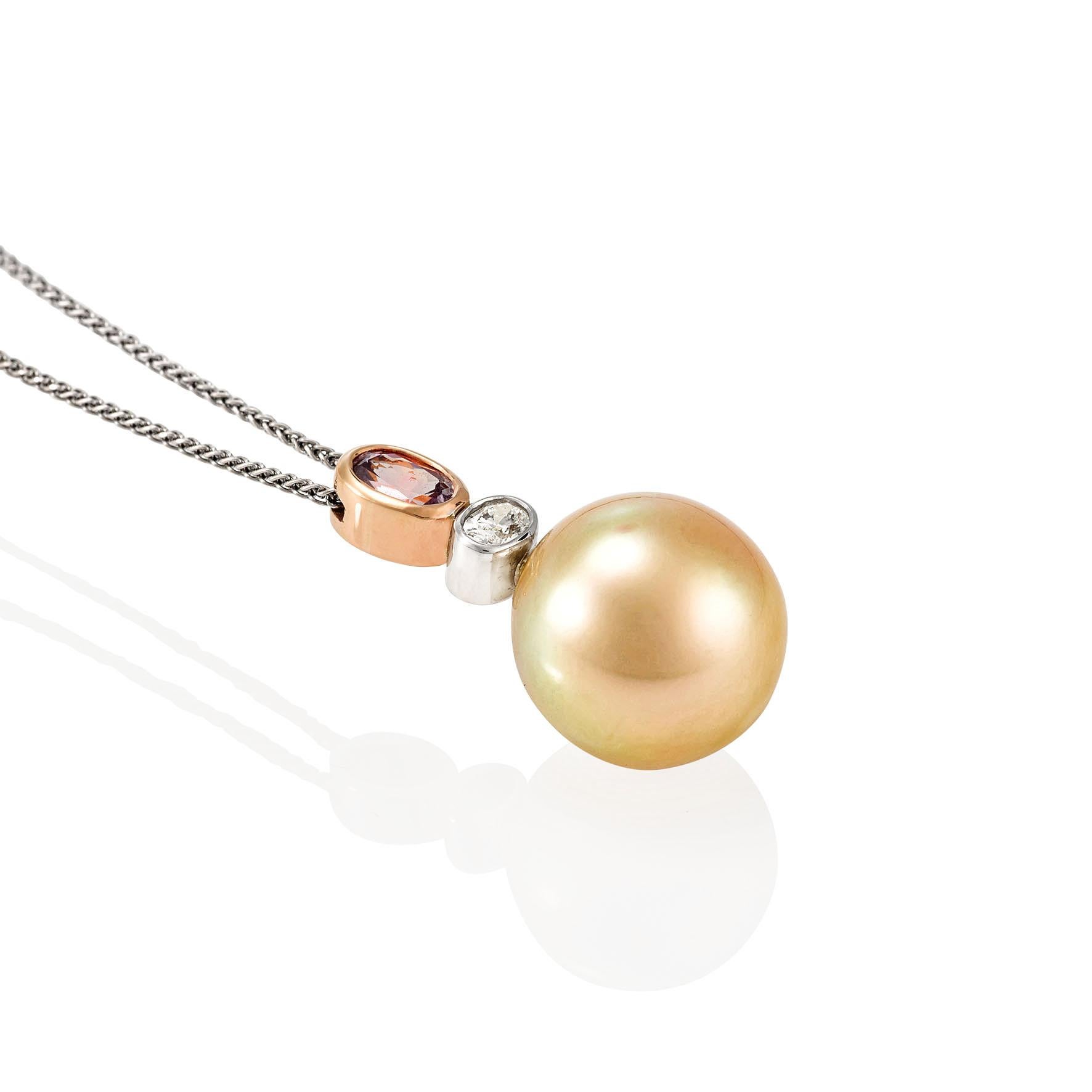 Giulians 18 karat Golden South Sea pearl, diamond and pink sapphire pendant. This pendant features one 14.2mm round, south sea cultured pearl with a high lustre and clean surface.  The bail features 0.19ct oval cut white diamond (F/VS) in an 18