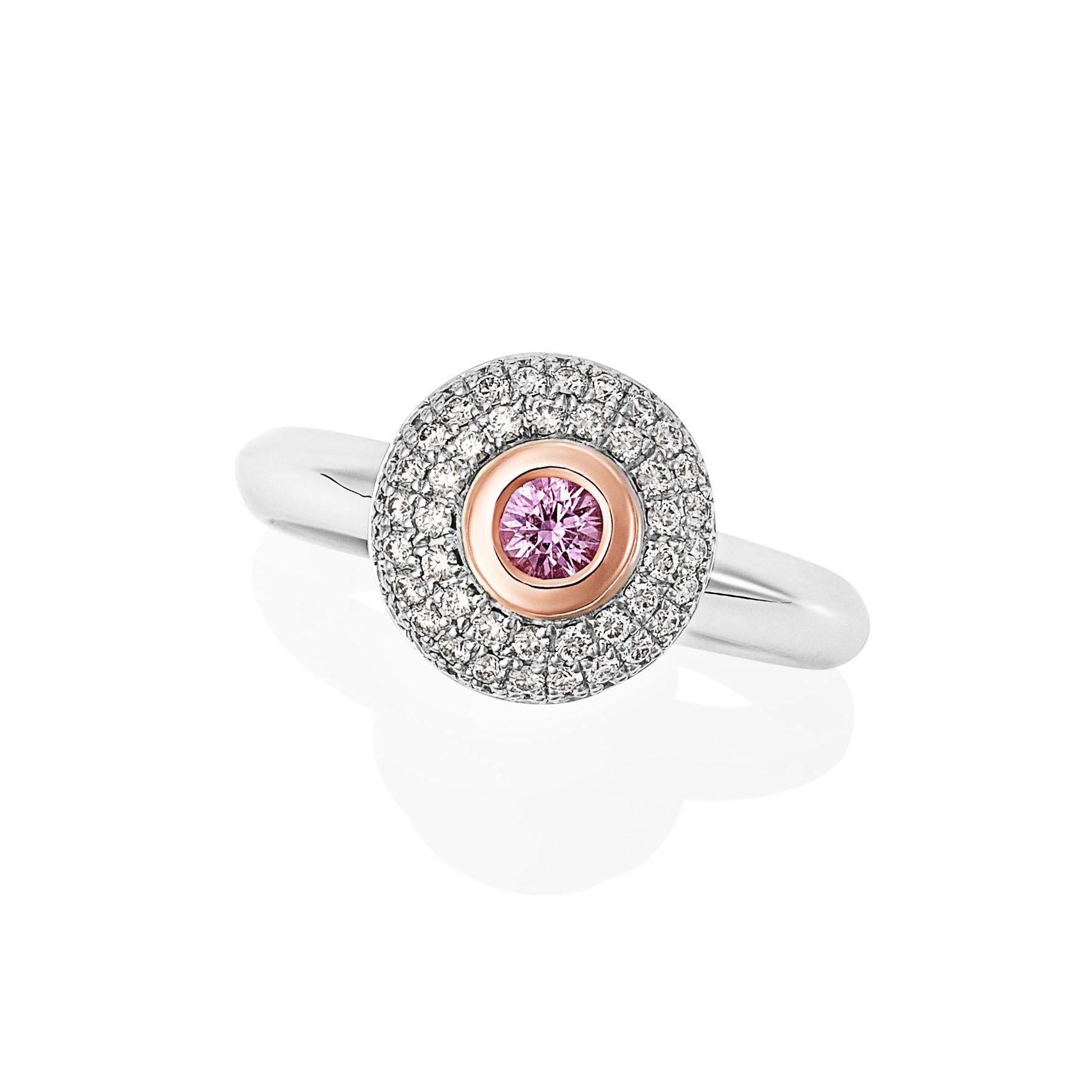 Giulians 18 karat rose and white gold pink sapphire and diamond ring.  This ring features a round diamond-cut 0.15ct pink sapphire in an 18 karat rose gold bezel setting.  The surrounding white gold domed plate is pave set with 68 round brilliant