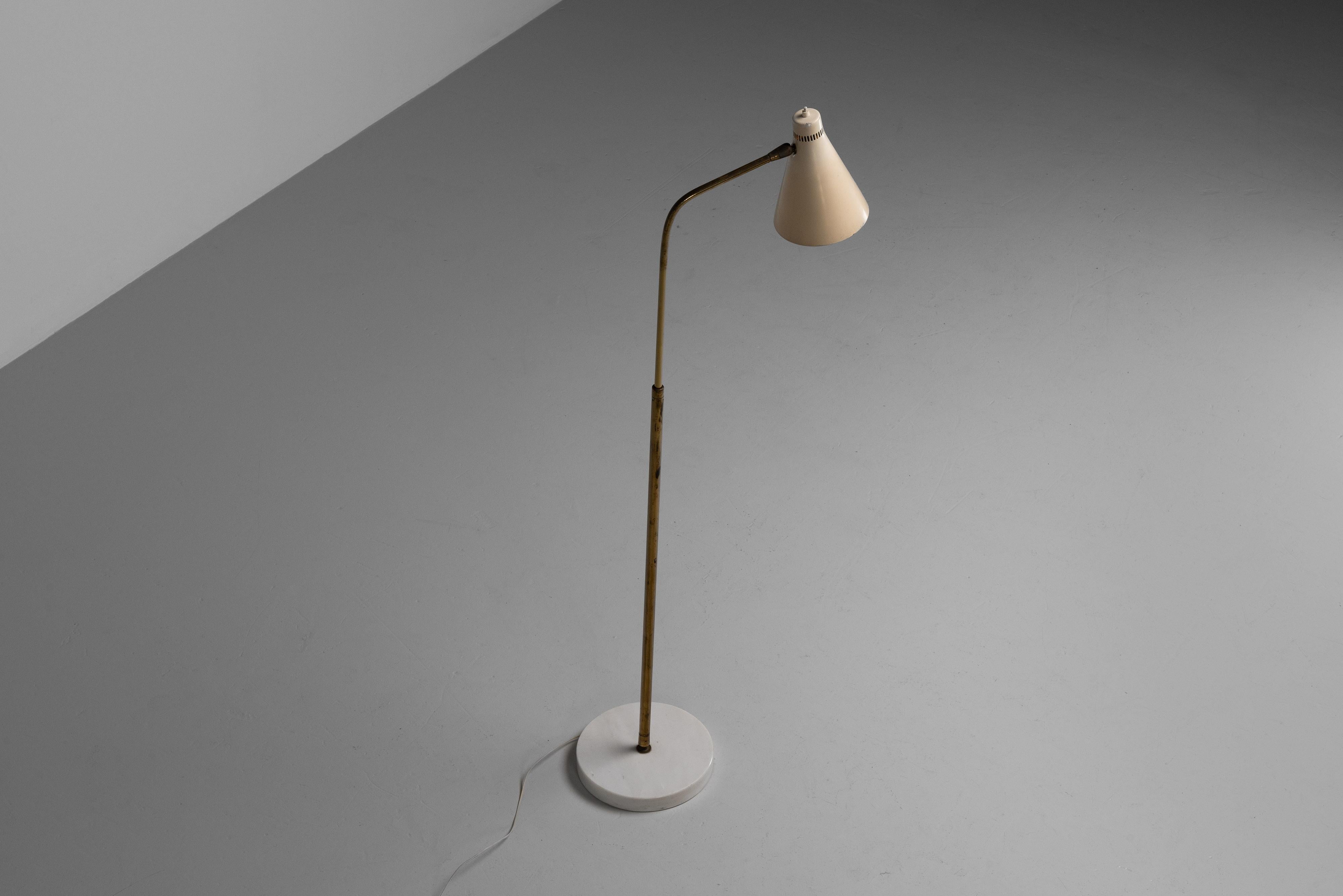 Reading lamp designed by Giuseppe Ostuni for Oluce in 1953. The lamps is in fully original with striking patina to the lamp. Adjustable in every direction and also in height. The lamp is characterized by a marble base, a telescopic brass stem and a