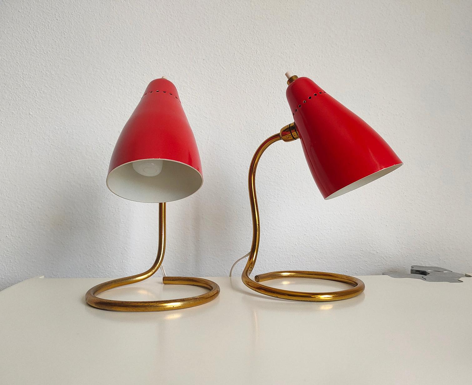 Set of two refined Italian lamps Mod. 214 produced by the famous company O-luce. 
The structure is in brass and characterized by sinuous lines. The lampshade is adjustable, with a particular asymmetrical shape and a beautiful 50s red
color.