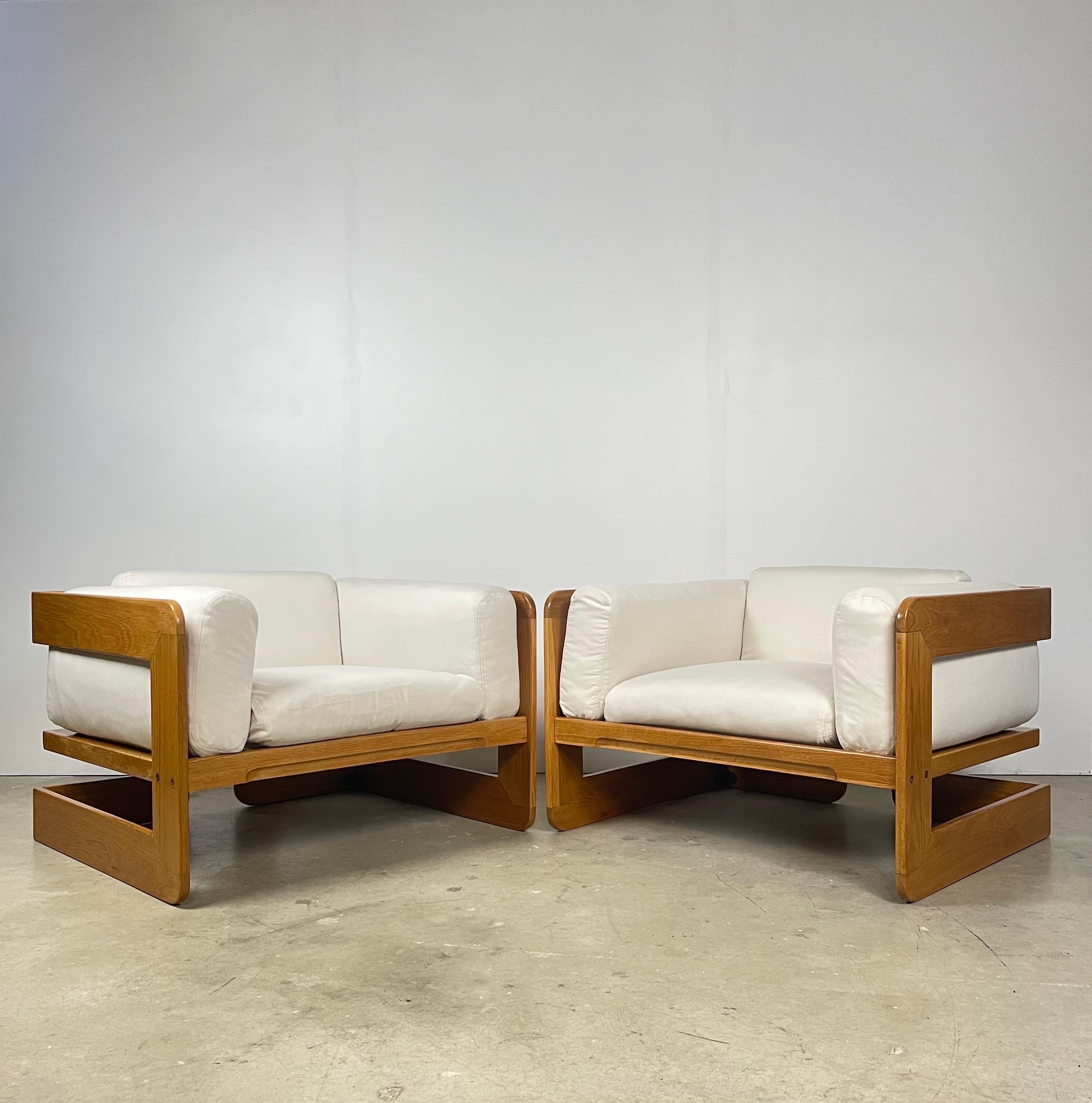 Set of two 1970s oak framed chairs designed by Giuseppe Raimondi. Frames have been refinished, natural flaws in wood remain that are indicative of the age of the pieces. Recommended to replace upholstery, some staining is present.