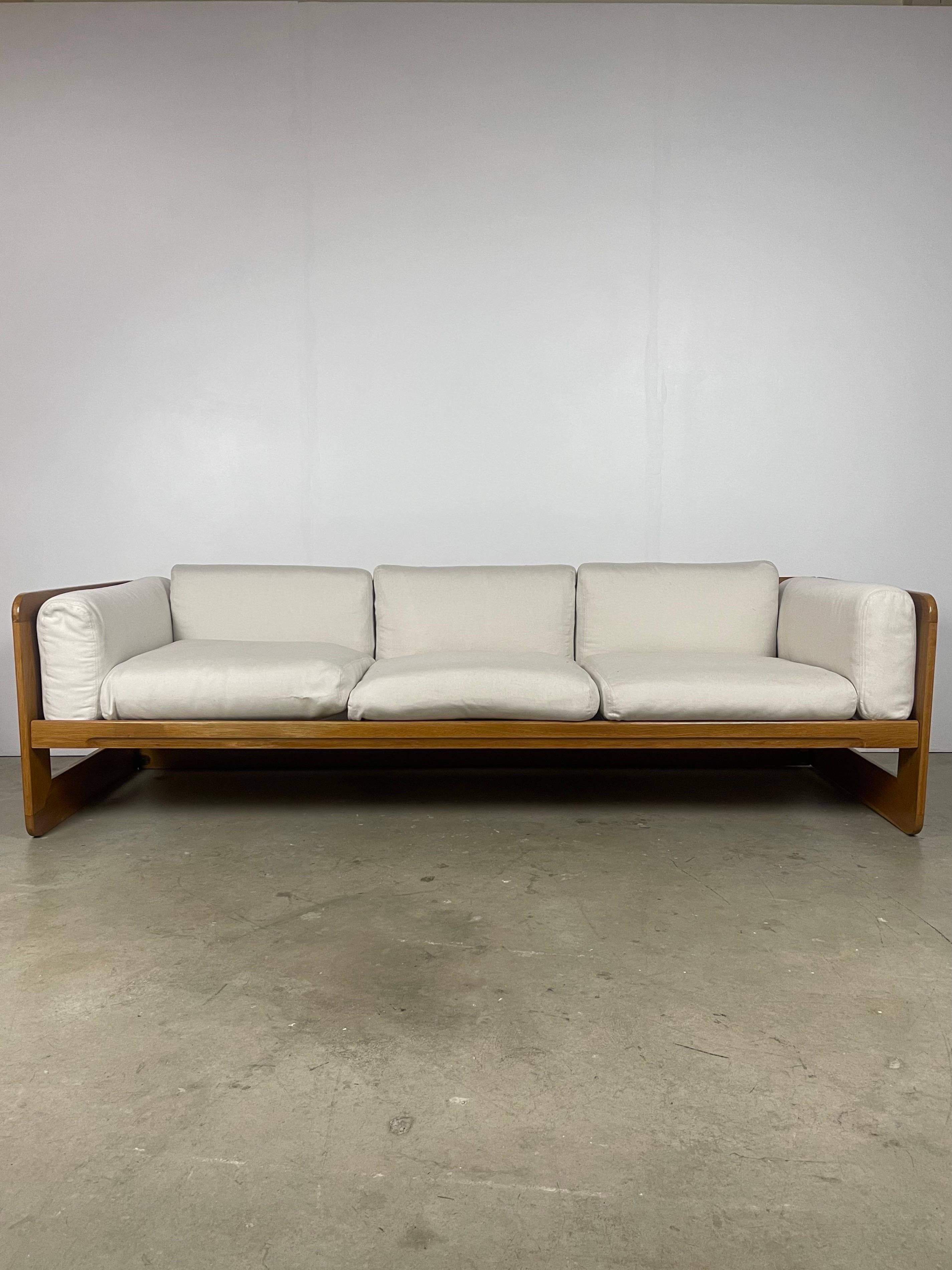 1970s oak framed sofa designed by Giuseppe Raimondi. Frame has been refinished- natural flaws and natural discrepancies in grain color remain. Recommended to replace upholstery- staining is present.