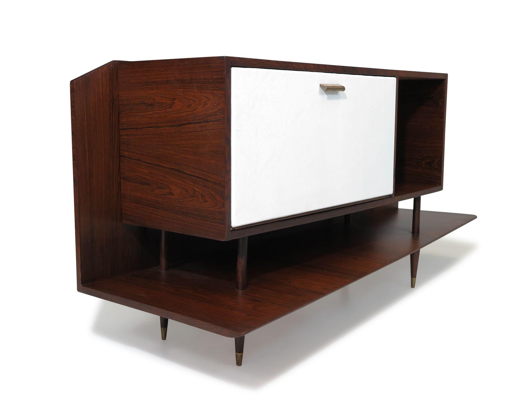 Brazilian Modern bar cabinet with an angular design attributed to Giuseppe Scapinelli, 1955, São Paulo, Brazil. This eye-catching and unique mid-century cabinet is crafted of Brazilian rosewood, and features a white vinyl-covered drop-front cabinet