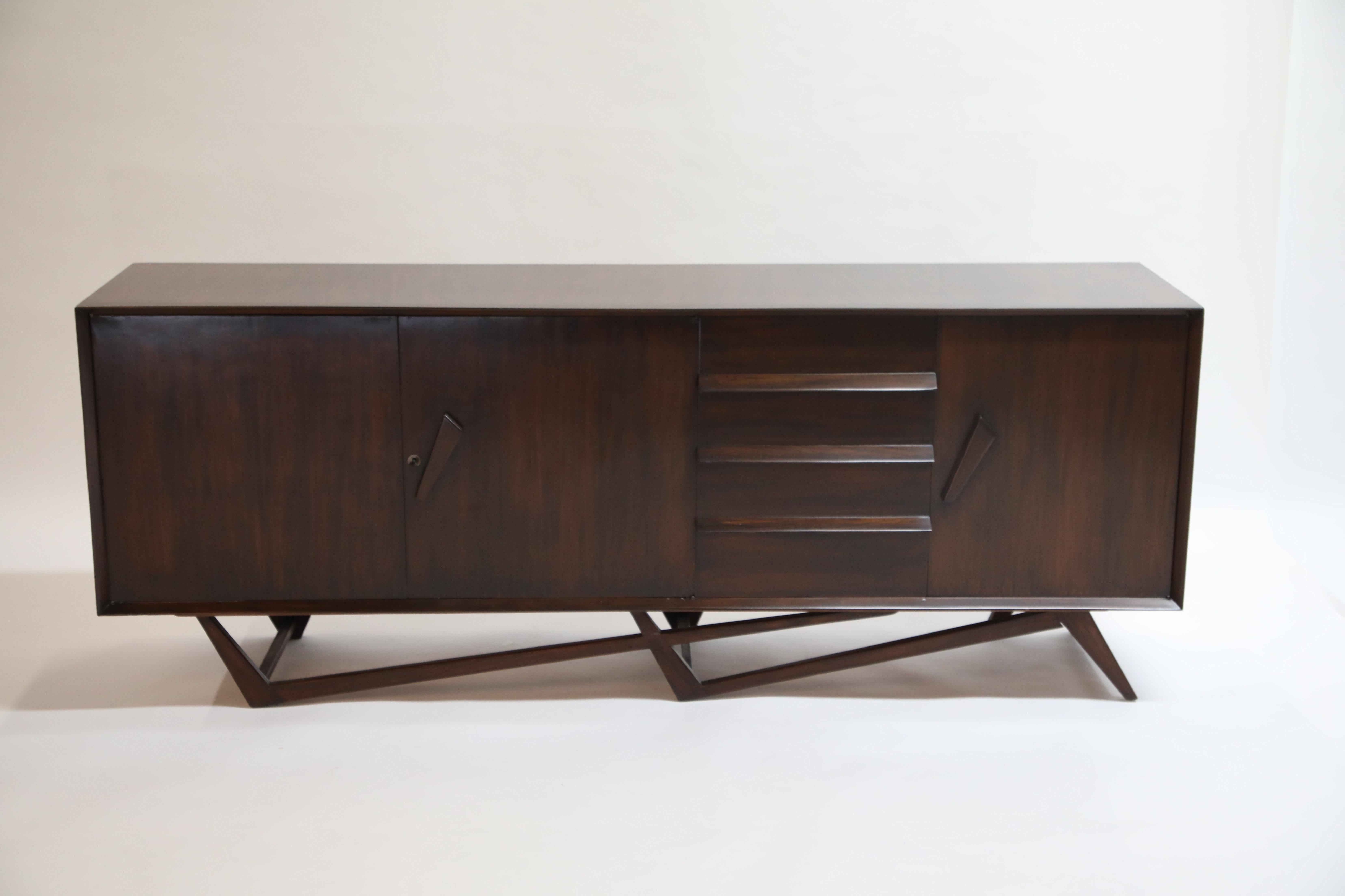 A breathtaking Giuseppe Scapinelli architectural sideboard, crafted in 1950s, Brazil. This incredible sideboard credenza, fabricated in a deep Brazilian Rosewood, sits atop a dual boomerang floating base. Wonderful googie styled handles open two