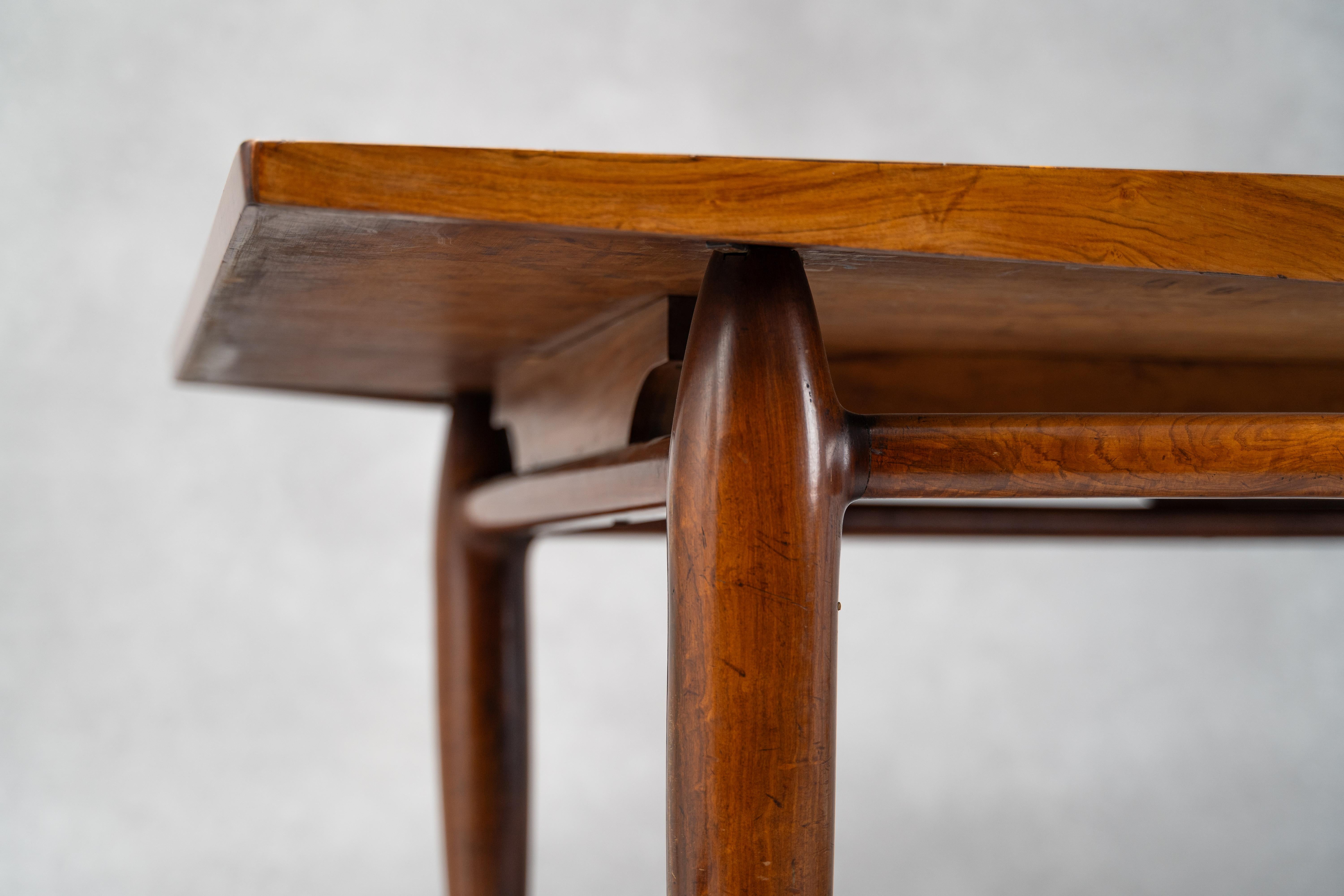 An elegant and sculptural dining by Italian-Brazilian designer Giuseppe Scapinelli, crafted in richly grained Caviuna wood. The sensuously carved frame curves downward along two sides, tapering to bullet-shaped legs joined by a sculptural arched