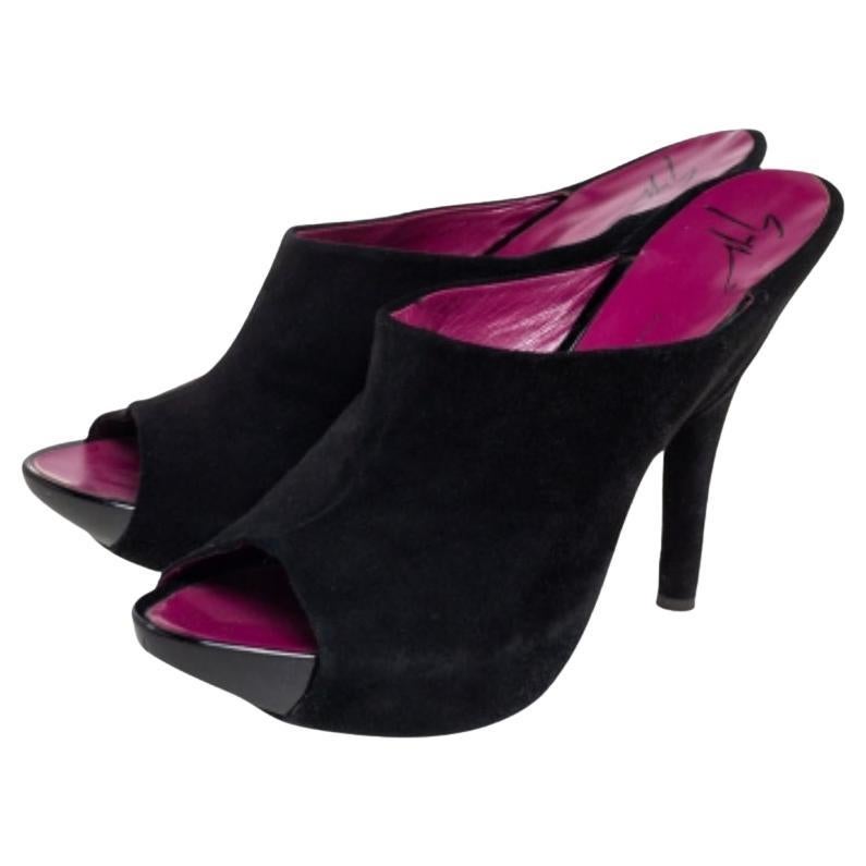 Diese umwerfenden Pantoletten von Giuseppe Zanotti stehen für Stil und Glamour. Sie sind aus schwarzem Wildleder gefertigt und haben eine schöne Silhouette. Diese zehenoffenen Sandalen haben einen 14 cm hohen Absatz, sind mit Leder gefüttert und