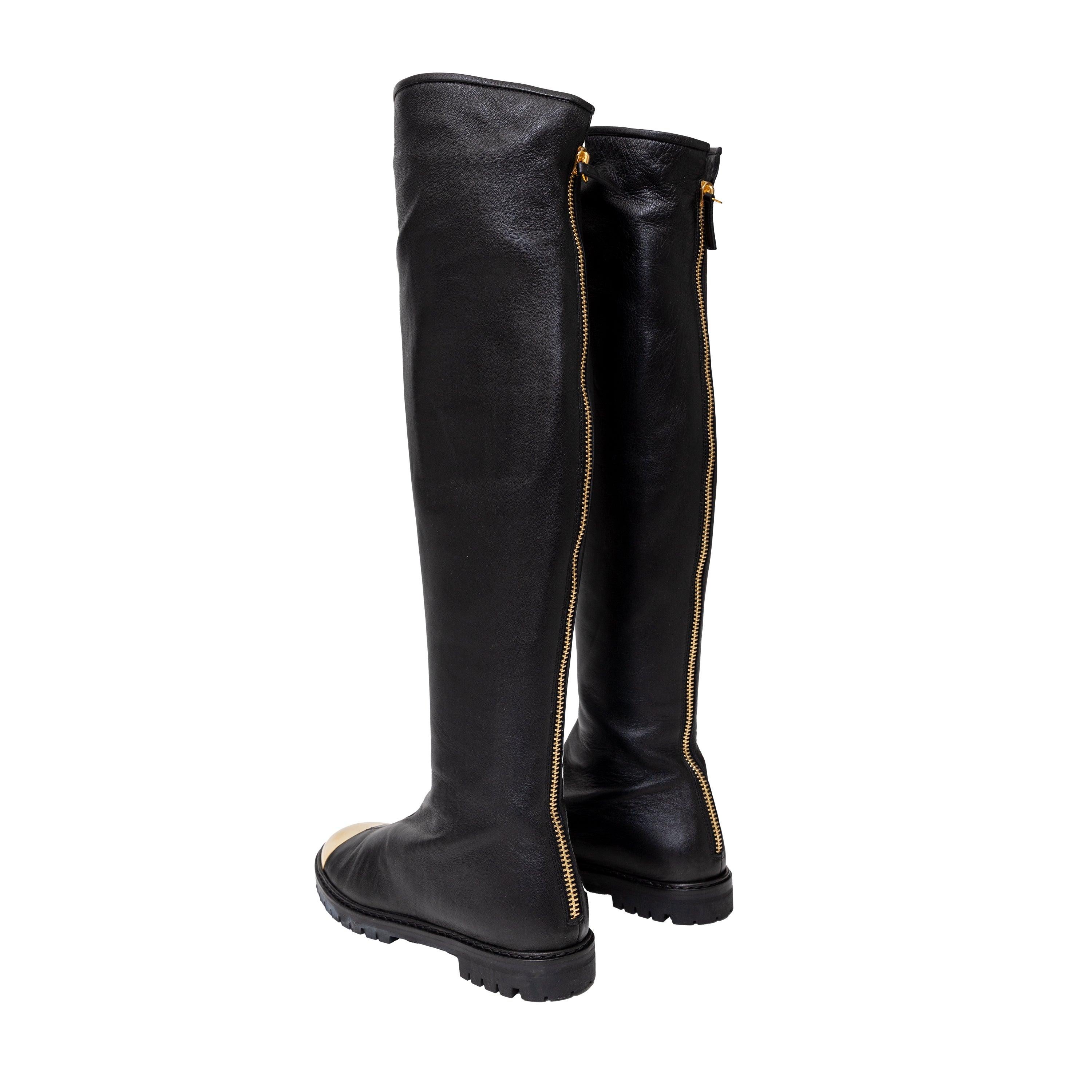 Eleva tu estilo con las botas de piel con puntera metálica Giuseppe Zanotti Dalila. Confeccionadas en suave piel negra, estas botas por encima de la rodilla presentan una elegante placa metálica dorada en la puntera. Con puntera redondeada, diseño