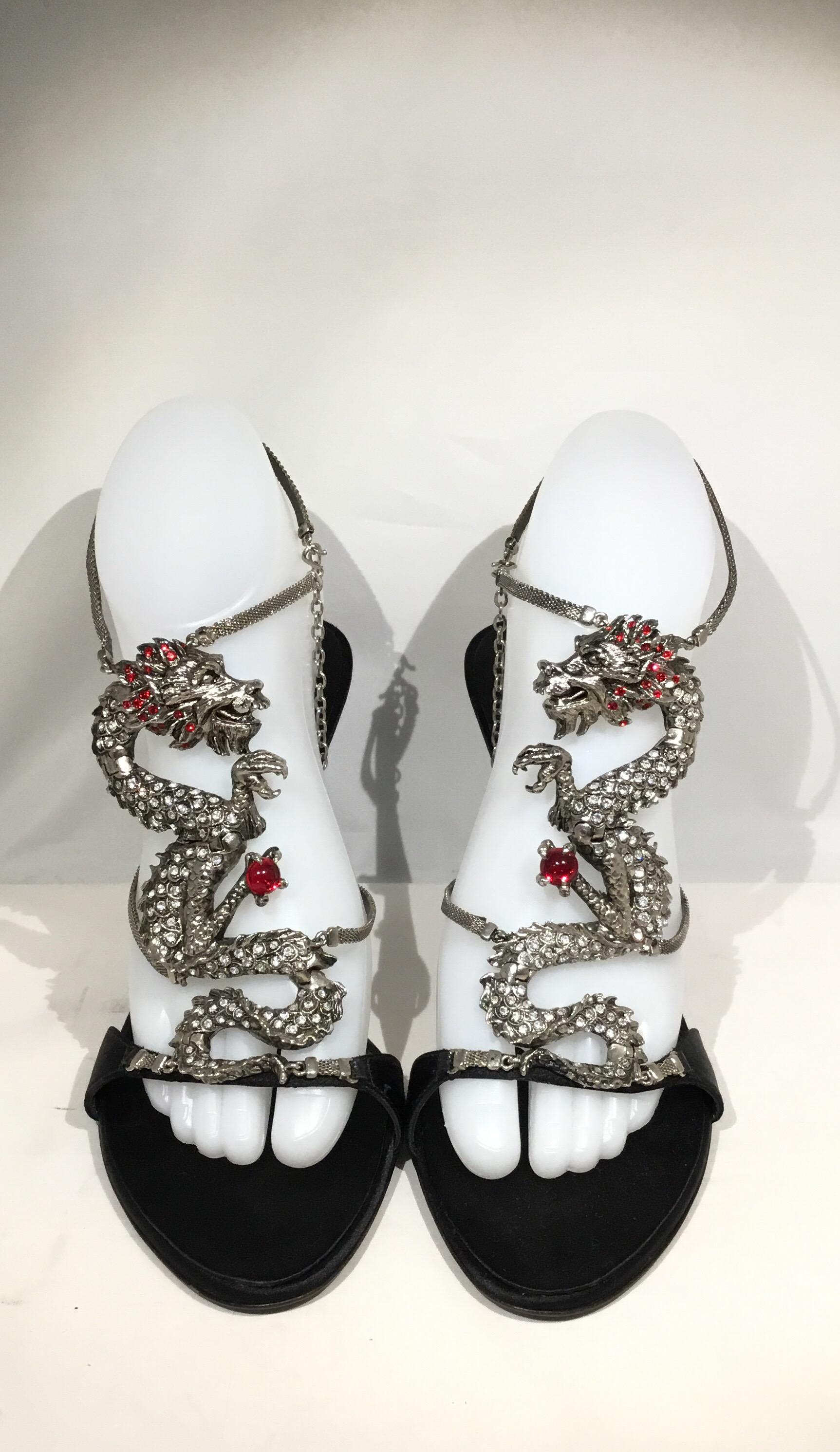 Giuseppe Zanotti Heels features an open toe style, a silver-tone Metal dragon detail encrusted with rhinestones and a red jewel. Heels have satin insoles, leather soles, an adjustable hook chain closure, and a 4-inch heel. 

Size 9 B, made in Italy.