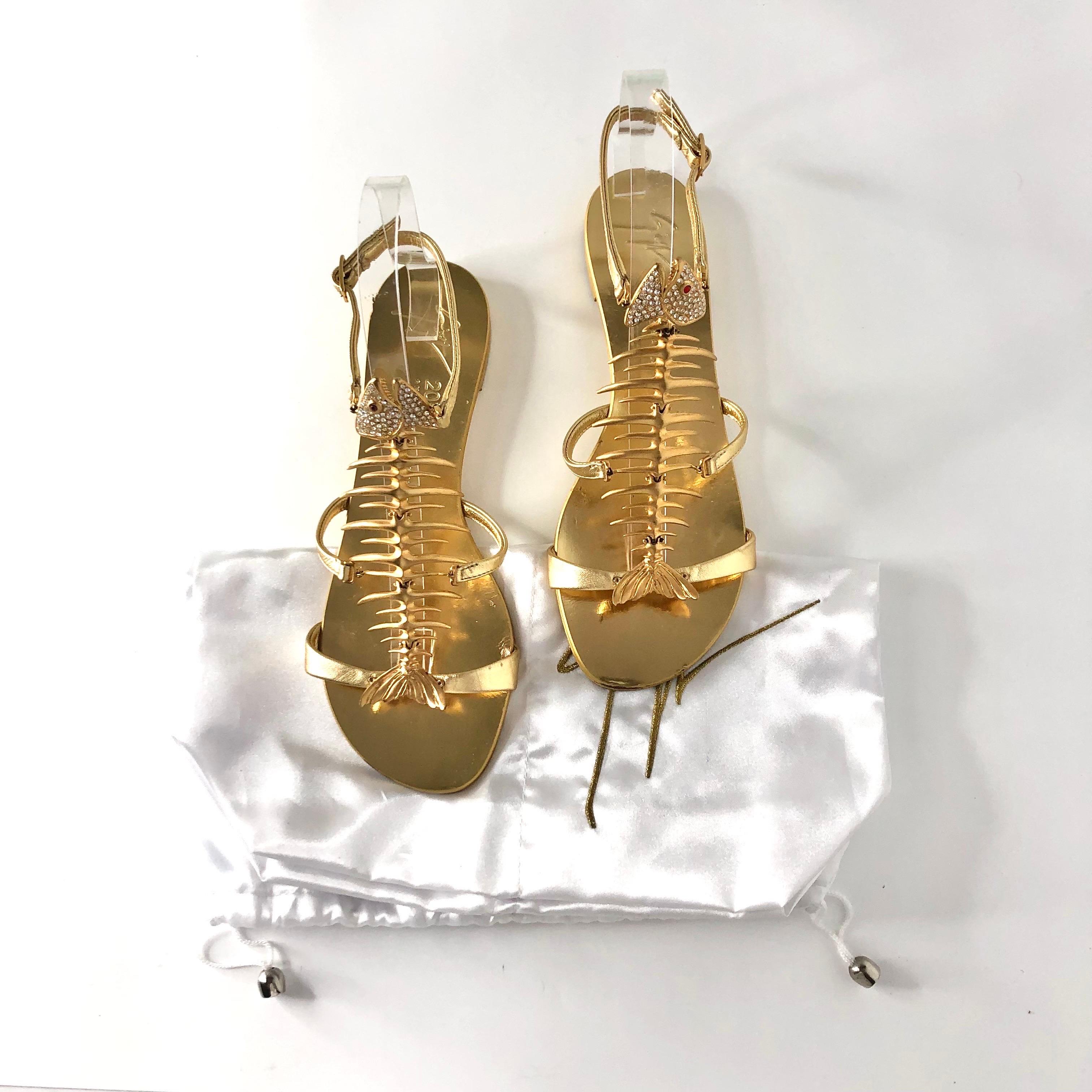 Giuseppe Zanotti - Sandales plates avec cristaux en arête de poisson
Avec sac à poussière
Couleur or
Taille 37 
Dessus en cuir
Semelle en cuir
Courroie ajustable
Squelette de poisson en métal avec finition dorée et cristaux
Il s'agit du style de