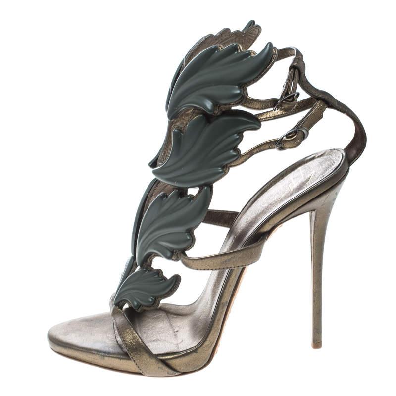 Wie könnte man sich nicht in diese auffälligen Argent Metal Wing Sandalen von Giuseppe Zanotti verlieben! Sie sind ein denkwürdiges Design dieses beliebten Schuhdesigners. Die Sandalen sind aus olivgrünem Leder gefertigt und mit Metallflügeln an der