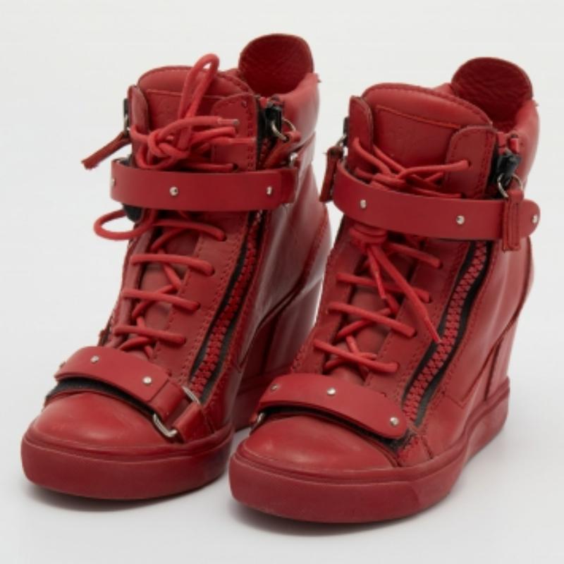 Elevate your style quotient with these Giuseppe Zanotti wedge sneakers. Crafted from red leather, these stunning creations are just what you need for everyday wear. The lace-up sneakers have two-tone metal hardware and tough rubber soles that add to