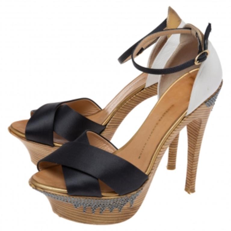 Reflect grace and elegance in each step with these Giuseppe Zanotti sandals. Constructed from satin and leather into an open-toe silhouette, they feature black criss-cross straps, covered-up counters, and ankle buckle closure. The embellished heels