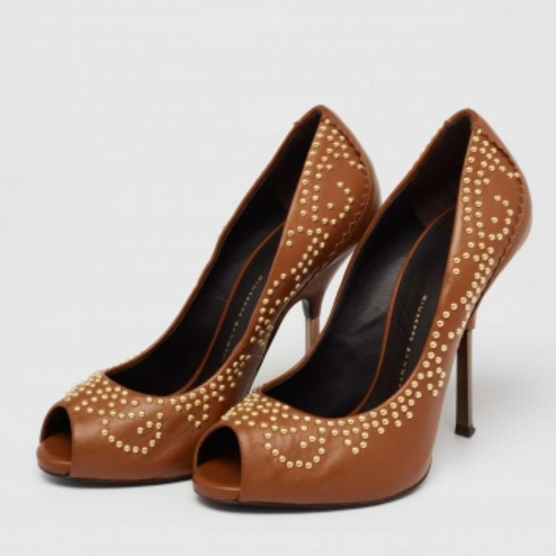 Exuding elegance, these Giuseppe Zanotti pumps are exceptional in design and appeal. Crafted in tan leather, the peep-toe pumps are studded with gold-tone rivets. They are elevated on 11.5 cm heels.