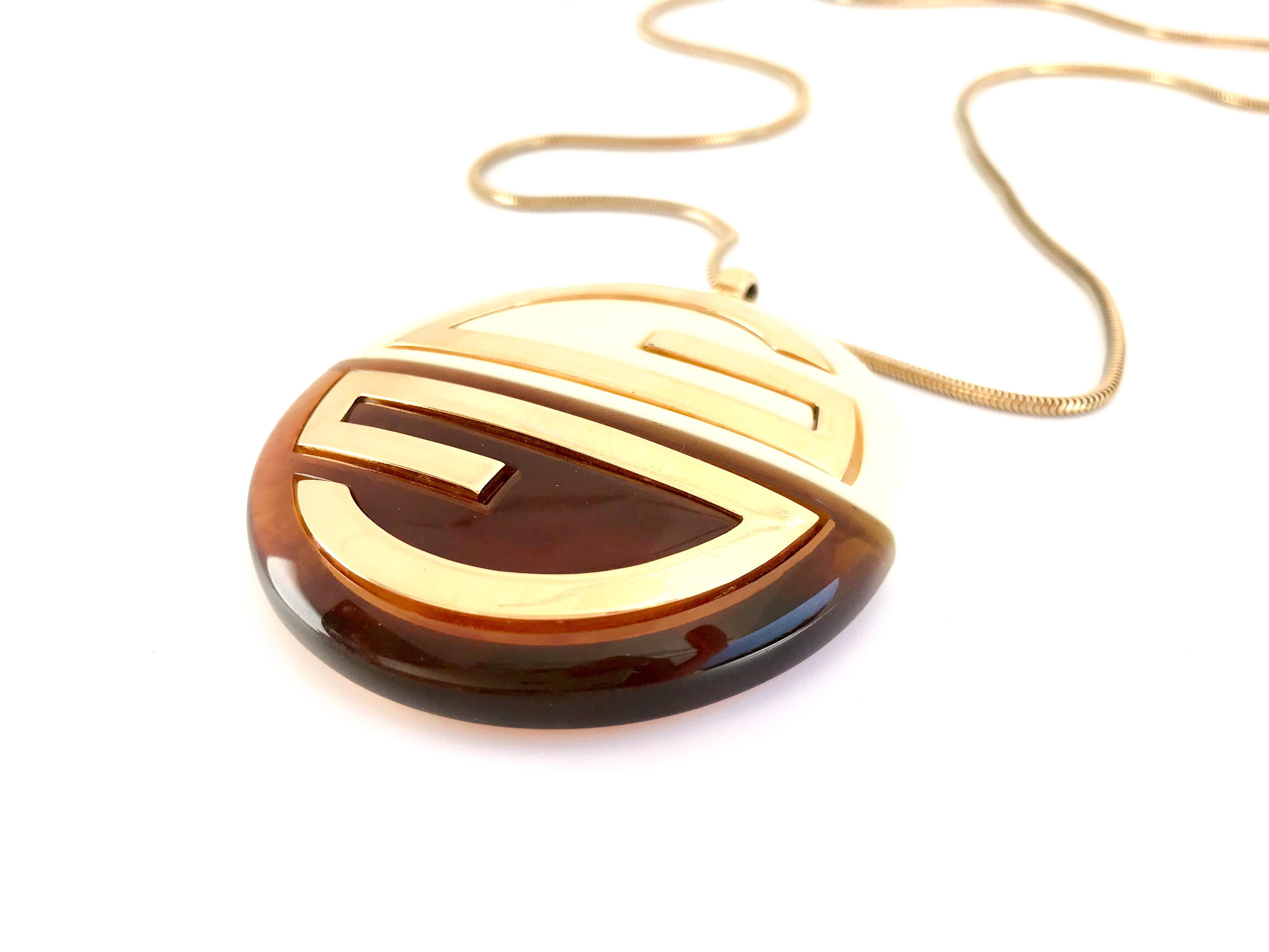 Givenchy 1970s Vintage Large Statement Pendant Necklace 

Beautiful snake chain made of gold tone metal and large lucite pendant with iconic Givenchy logo embossed in gold metal.

Pendant measures 2.5 inches across
Chain is 27 inches long

Chain and