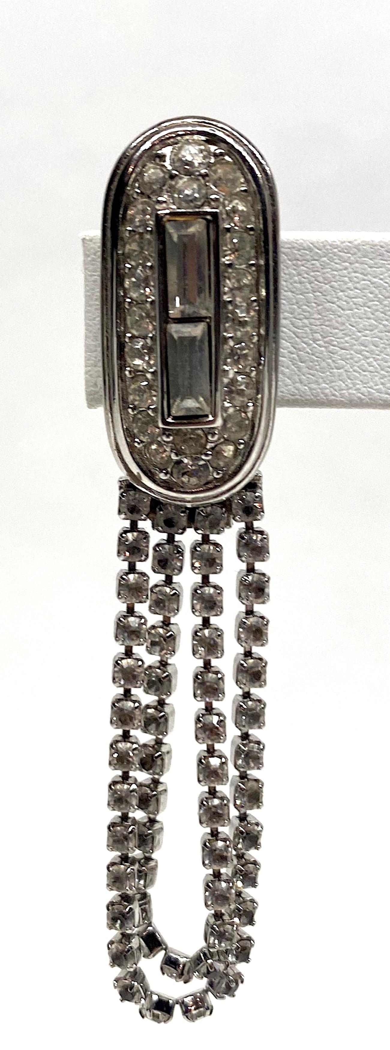 A lovely pair of 1980s Givenchy Art Deco style rhinestone loop fringe earrings in rhodium plate. Each earring is comprised of a .5 of an inch wide and 1.13 of an inch long oval top piece. It is set with two rhinestone baguettes down the center and
