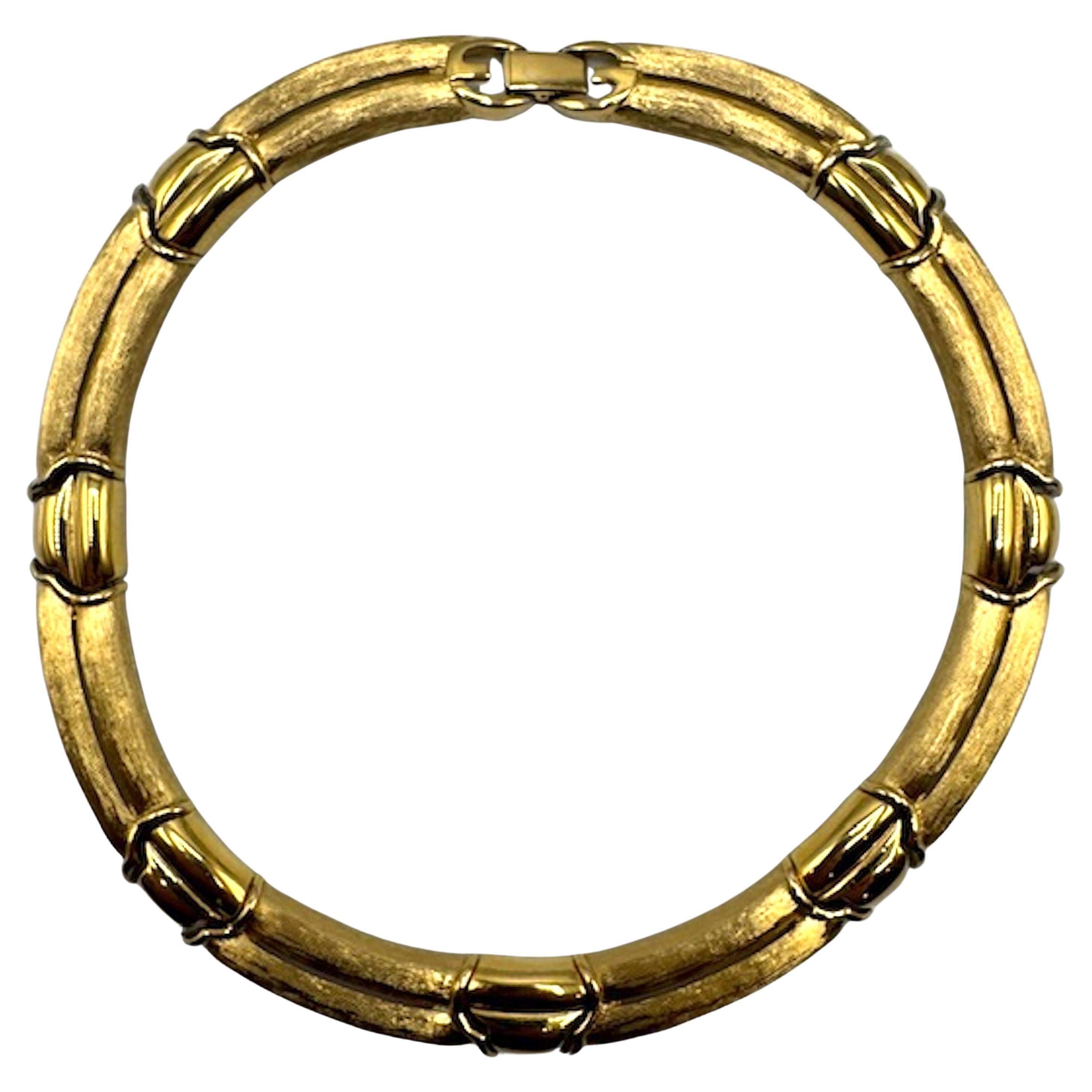 Collier Vintage By Givenchy des années 1980 avec finition luxueuse en ton or. La pièce est composée de 15 maillons incurvés, dont 8 longs et 7 courts, dans un faux motif à double brin. Les maillons longs en finition or satiné sont fendus en leur