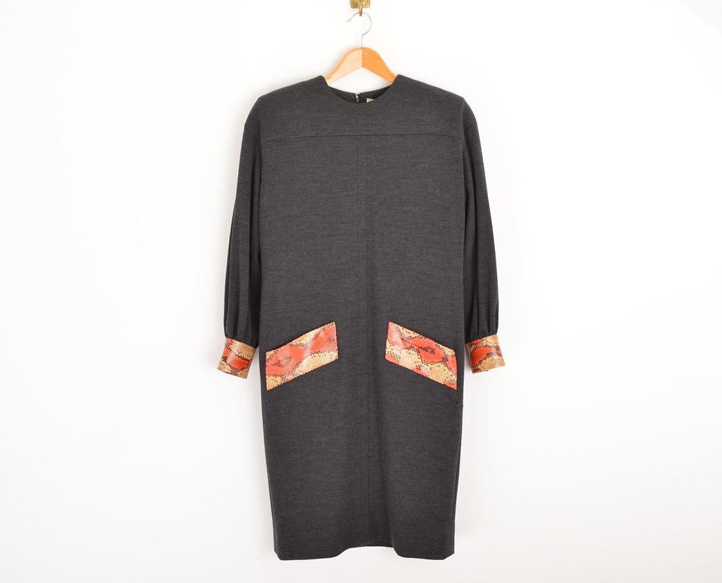 Anthrazitfarbenes Cocktailkleid des Labels 'NOUVELLE BOUTIQUE' von Givenchy aus den 1980er Jahren mit gepolsterten Schultern, langen Ärmeln und einem Saum, der knapp über das Knie reicht. Das Kleid ist mit exotischen Fellen aus creme- und