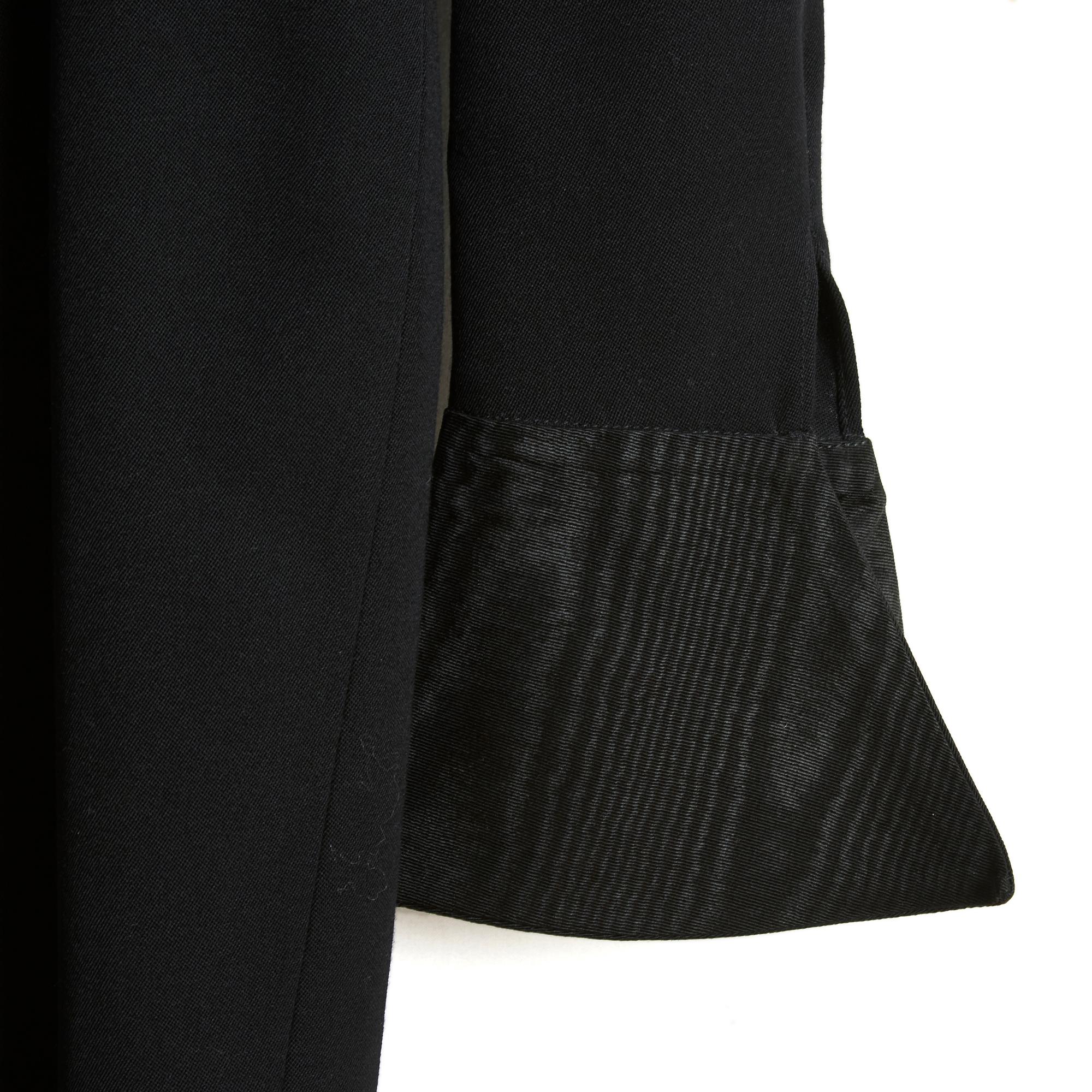 Givenchy dress circa 1990 in black wool cloth, sheath shape, wide boat neck, long sleeves extended by a musketeer-style cuff in black silk or wool moire, black satin canvas lining, fastened with a long zip and a hook in the back. No more composition