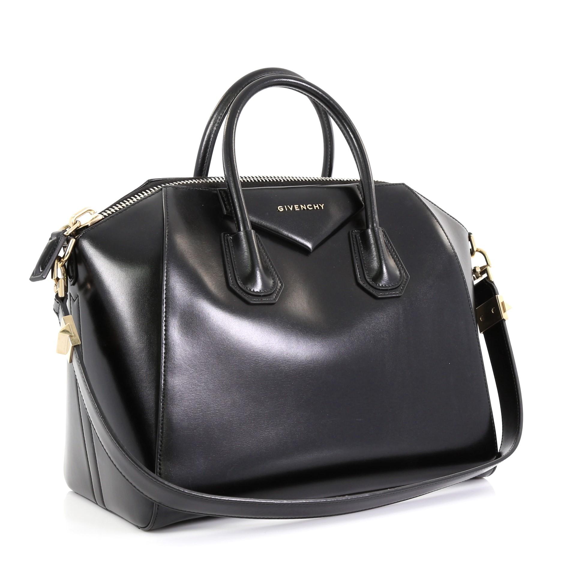 This Givenchy Antigona Bag Glazed Leather Medium, crafted from black glazed leather, features dual rolled leather handles and gold-tone hardware. Its zip closure opens to a black fabric interior with zip and slip pockets. 

Estimated Retail Price:
