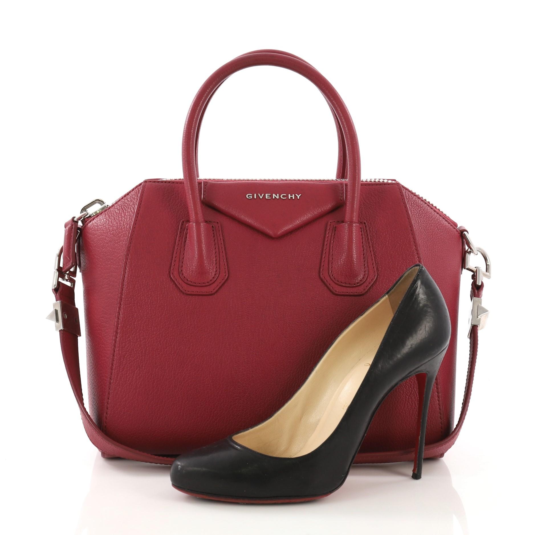 This Givenchy Antigona Bag Leather Small, crafted from fuchsia leather, features dual rolled leather handles and silver-tone hardware. Its zip-around closure opens to a beige fabric interior with zip and slip pockets. **Note: Shoe photographed is