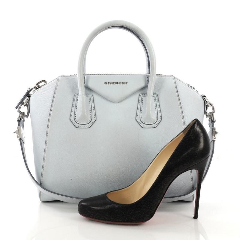 This Givenchy Antigona Bag Leather Small, crafted from light blue leather, features dual rolled leather handles and silver-tone hardware. Its zip-around closure opens to a beige fabric interior with zip and slip pockets. **Note: Shoe photographed is