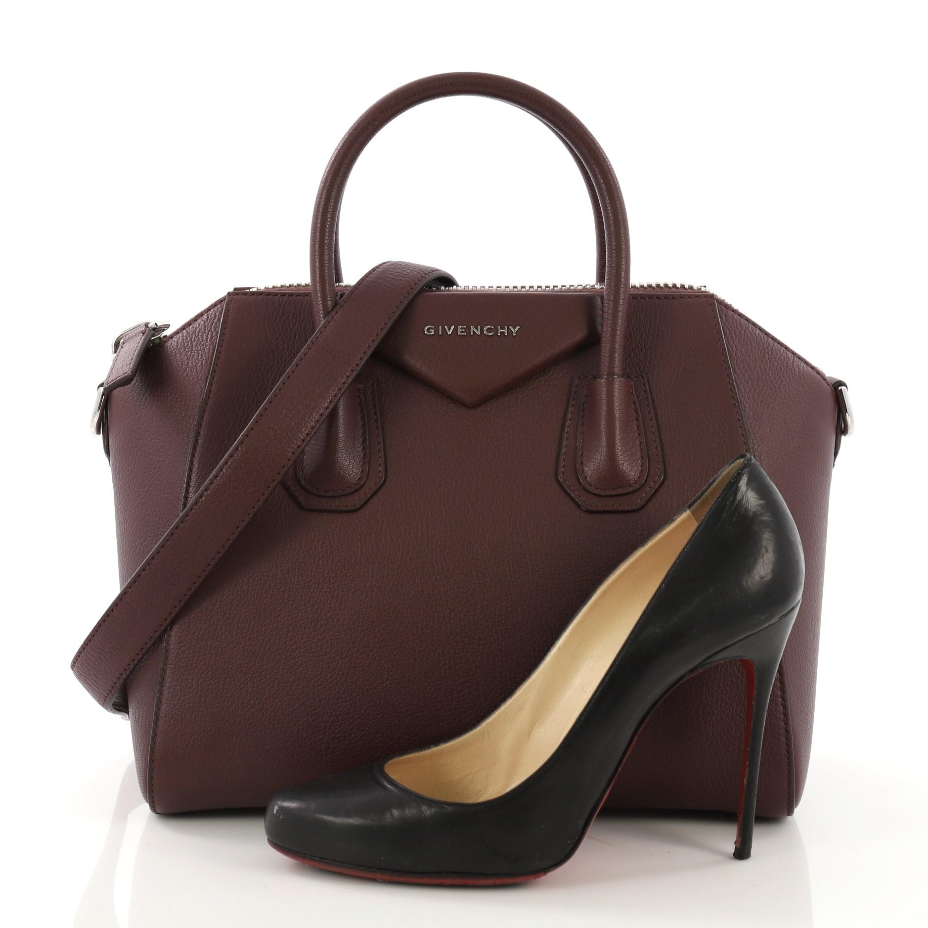 This Givenchy Antigona Bag Leather Small, crafted from burgundy leather, features dual top handles and silver-tone hardware. Its zip closure opens to a beige fabric interior with side zip and slip pockets. **Note: Shoe photographed is used as a