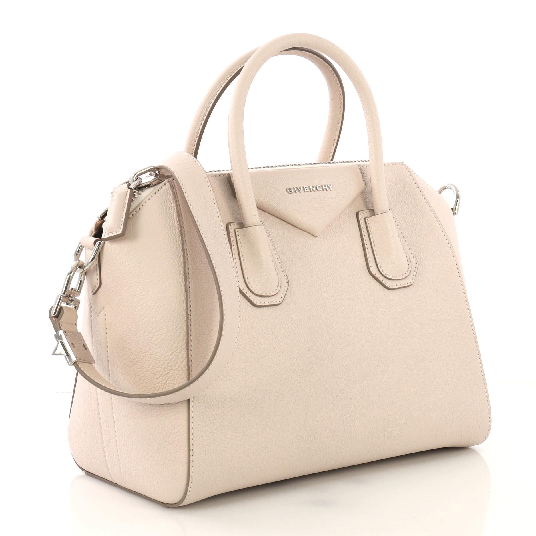 This Givenchy Antigona Bag Leather Small, crafted from pale pink leather, features dual rolled leather handles and silver-tone hardware. Its zip closure opens to a beige fabric interior with zip and slip pockets. 

Estimated Retail Price: