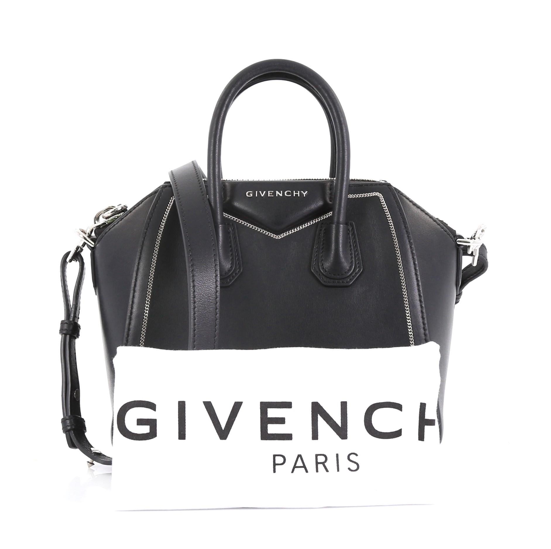 This Givenchy Antigona Bag Leather with Chain Detail Mini, crafted from black leather, features signature envelope flap detail with Givenchy logo, dual rolled leather handles, chain link detailing, and silver-tone hardware. Its zip closure opens to