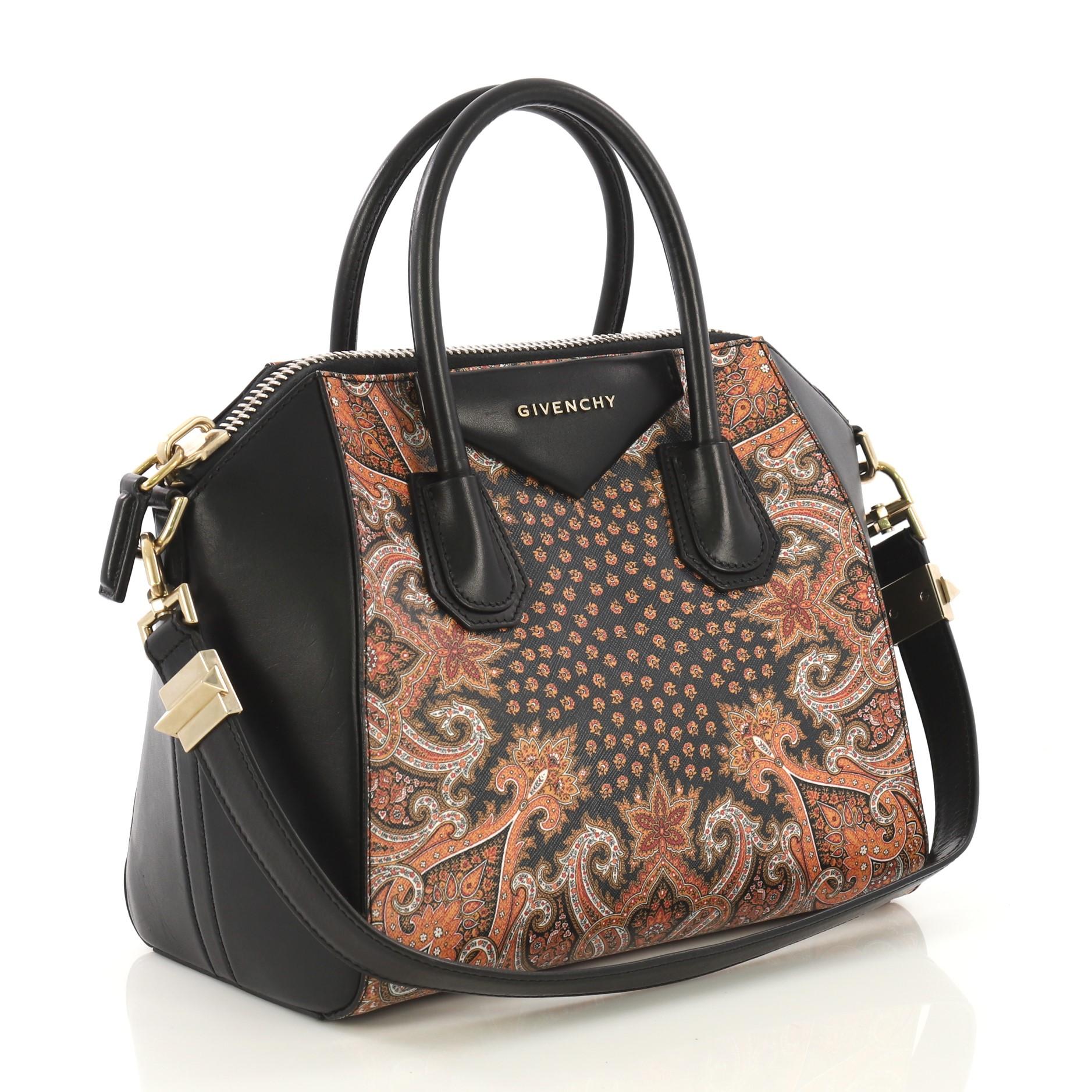 This Givenchy Antigona Bag Printed Leather Mini, crafted from black printed leather, features dual rolled leather handles and gold-tone hardware. Its zip-around closure opens to a black fabric interior with zip and slip pockets. 

Estimated Retail