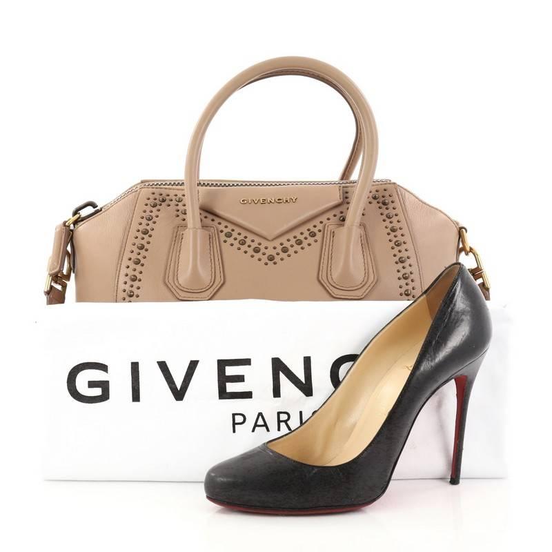 This authentic Givenchy Antigona Bag Studded Leather Small is a go-to fashion favourite. Crafted from smooth nude leather, this structured yet stylish tote features dual-rolled leather handles, aged gold stud detailing, a flat shoulder strap,