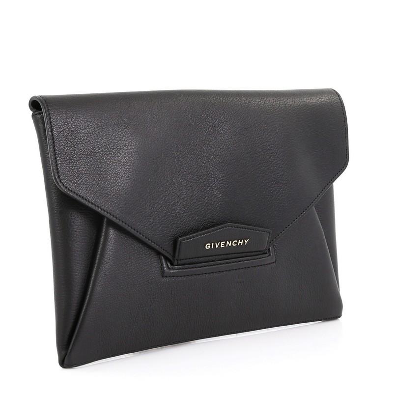 This Givenchy Antigona Envelope Clutch Leather Medium, crafted in black leather, features an envelope flap with raised Givenchy logo, magnetic flap that tucks into slot, and silver-tone hardware. Its flap opens to a black fabric interior divided