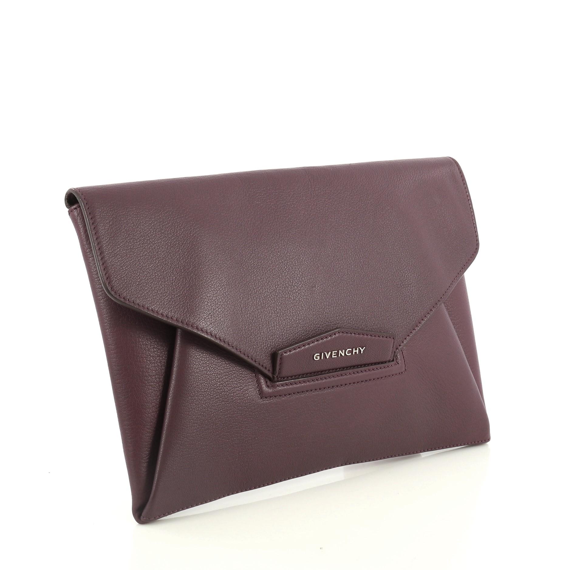 This Givenchy Antigona Envelope Clutch Leather Medium, crafted in purple leather, features an envelope flap top with raised Givenchy logo, magnetic flap that tucks into slot, and silver-tone hardware. Its flap opens to a neutral fabric interior