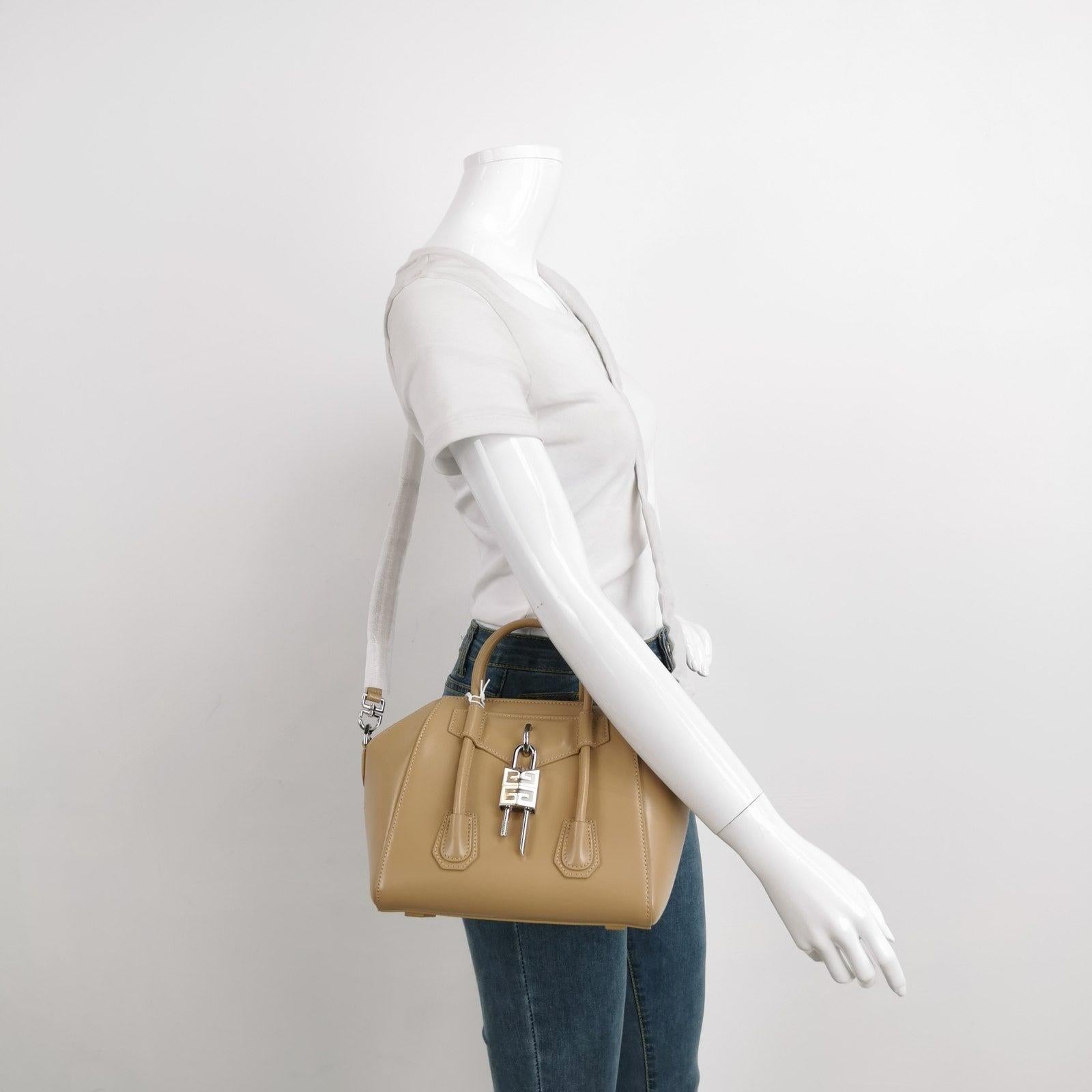 Givenchy Antigona Lock Mini Beige Smooth Leather Top Handle bag with Strap
 These are professional photos of the actual bag offered by Luxbags.
 The addition of the lock and lowered strap elevates a classic design, the Givenchy Antigona, with an