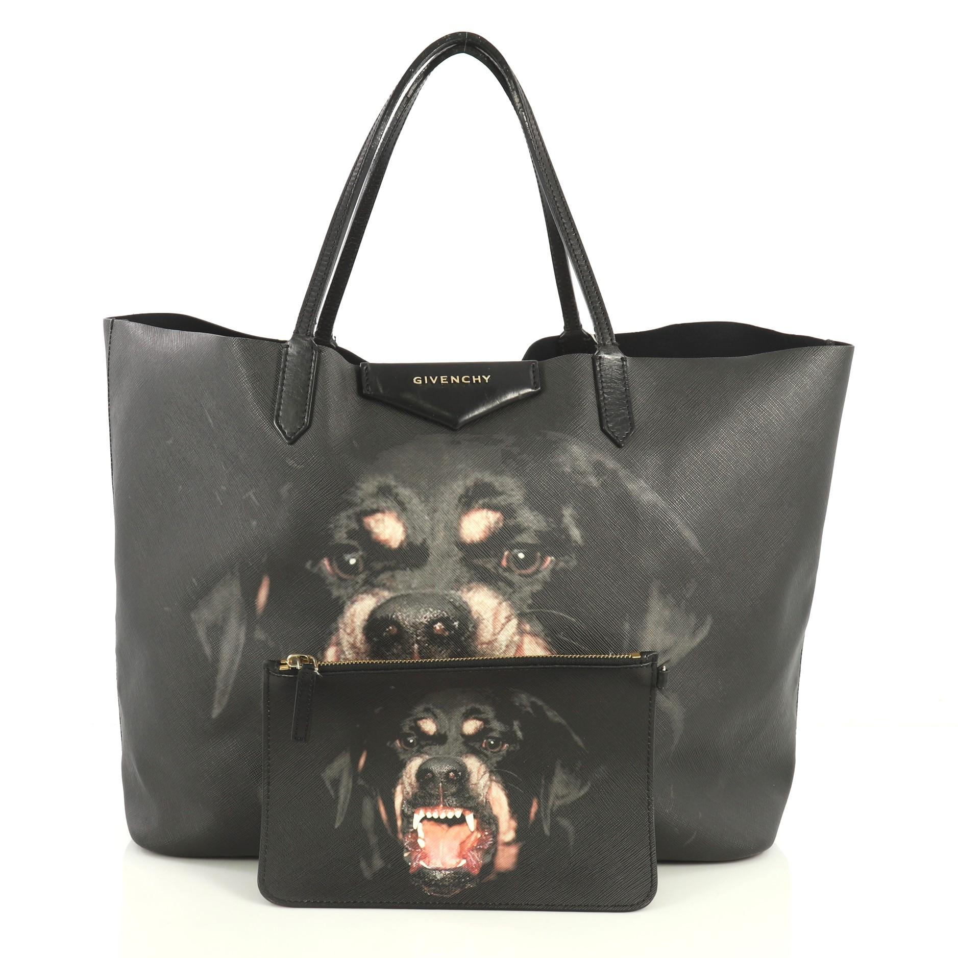 This Givenchy Antigona Shopper Printed Coated Canvas Large, crafted in black coated canvas, features dual-leather slim handles, an oversized Rottweiler dog print, Givenchy's raised envelope logo, and gold-tone hardware. Its wide open top showcases a